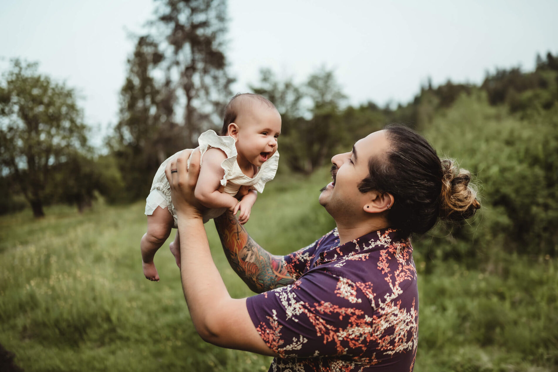 Dad holding his toddler daughter high in his arms and playing with her