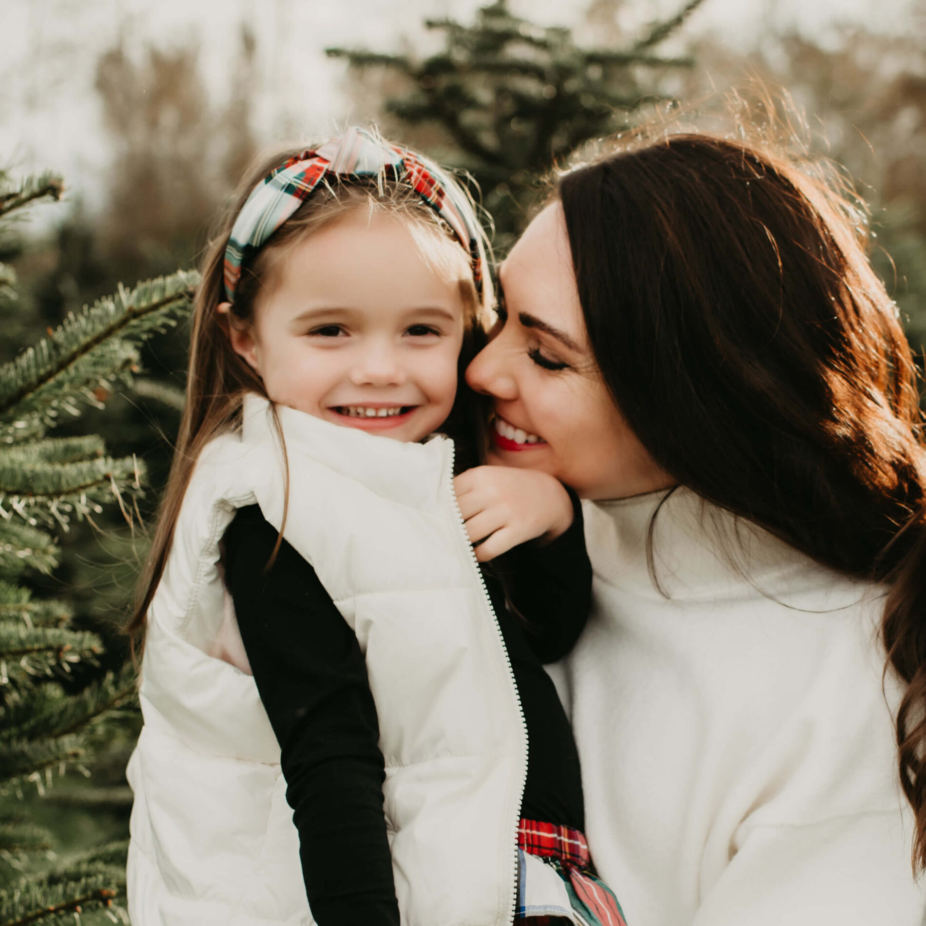 Woman hugging her daughter at a Christmas tree farm