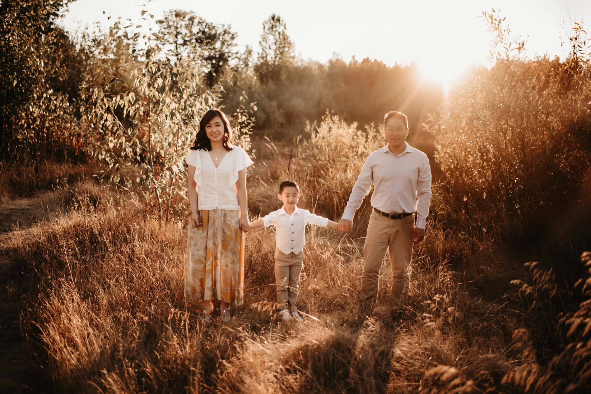 A photo shoot of a tastefully dressed family standing in a field with tall grass in Redmond, WA