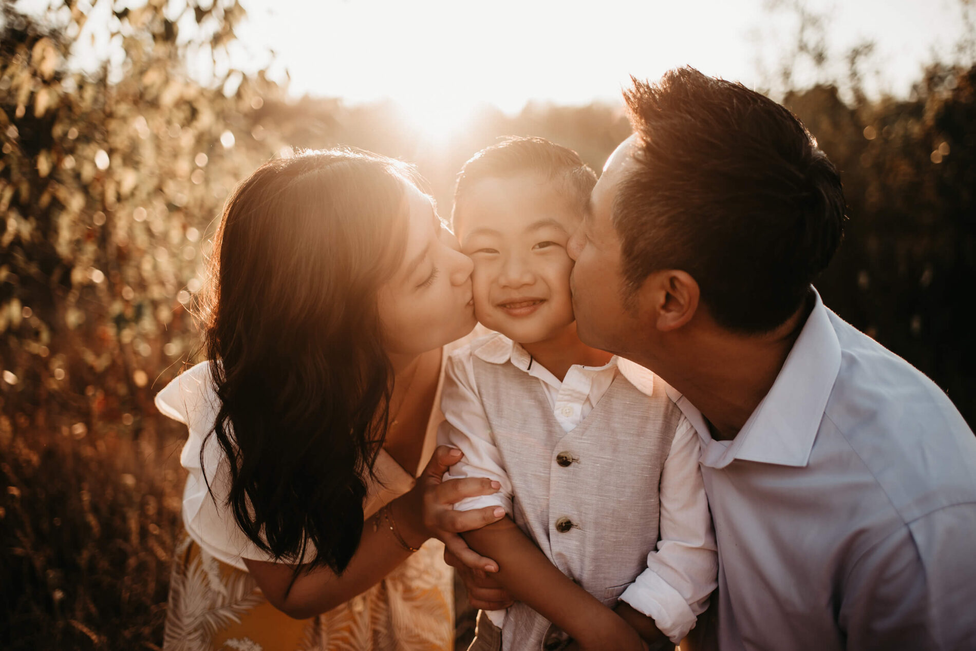 Family portrait of mom and dad kissing their son