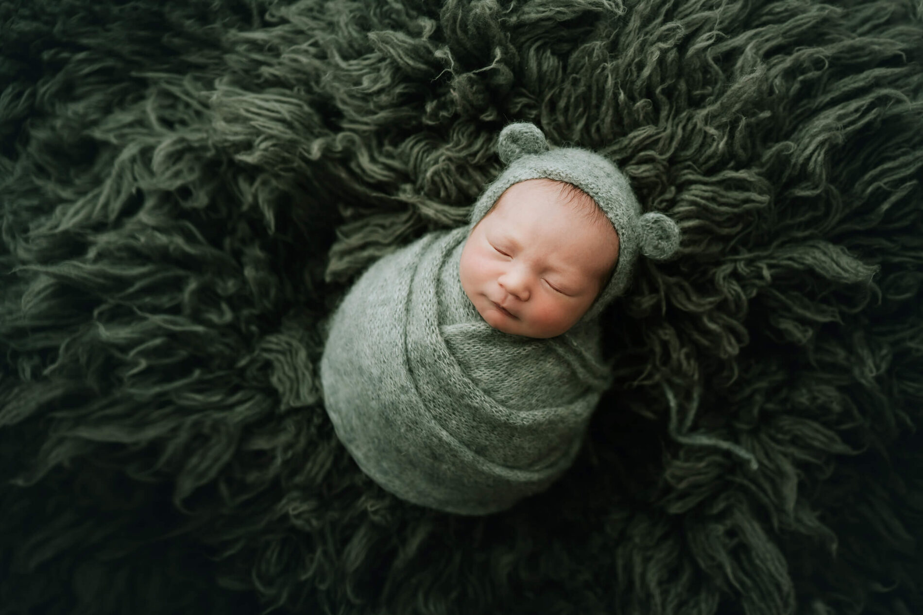 Newborn photo shoot: a newborn boy beautifully wrapped in a green blanket