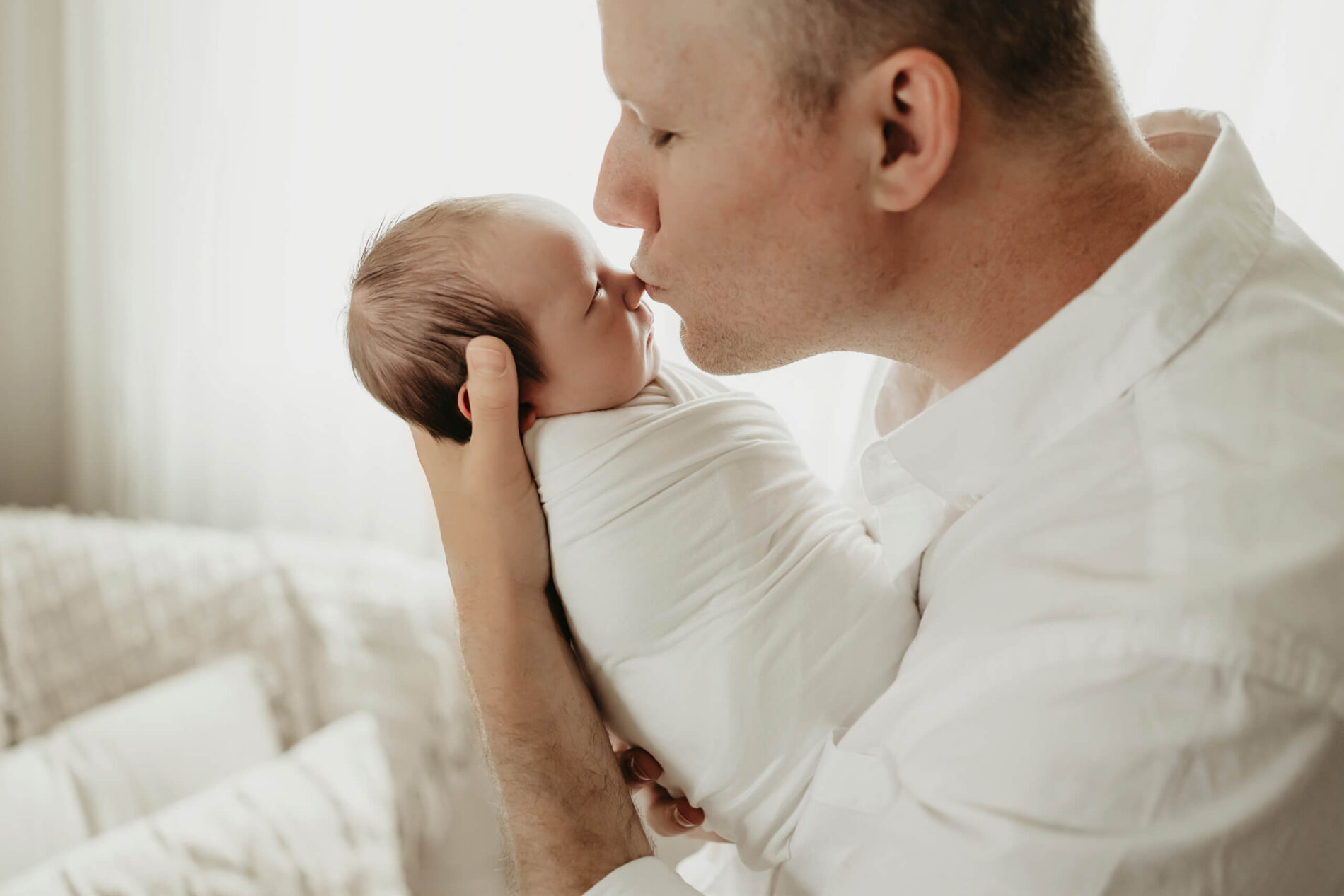 Newborn photo shoot of dad kissing his newborn son