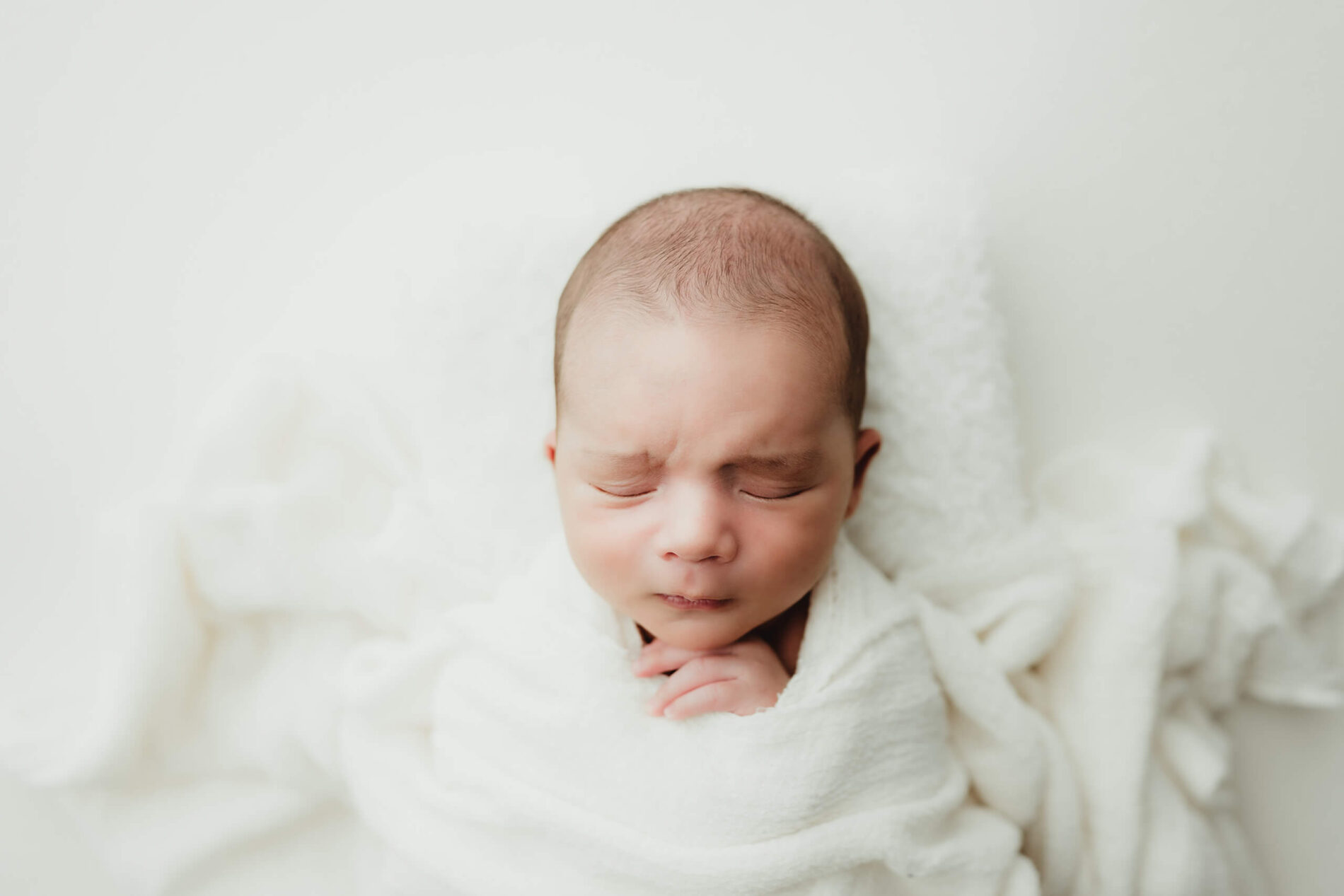 Newborn photography session: cozily-wrapped sleeping newborn boy