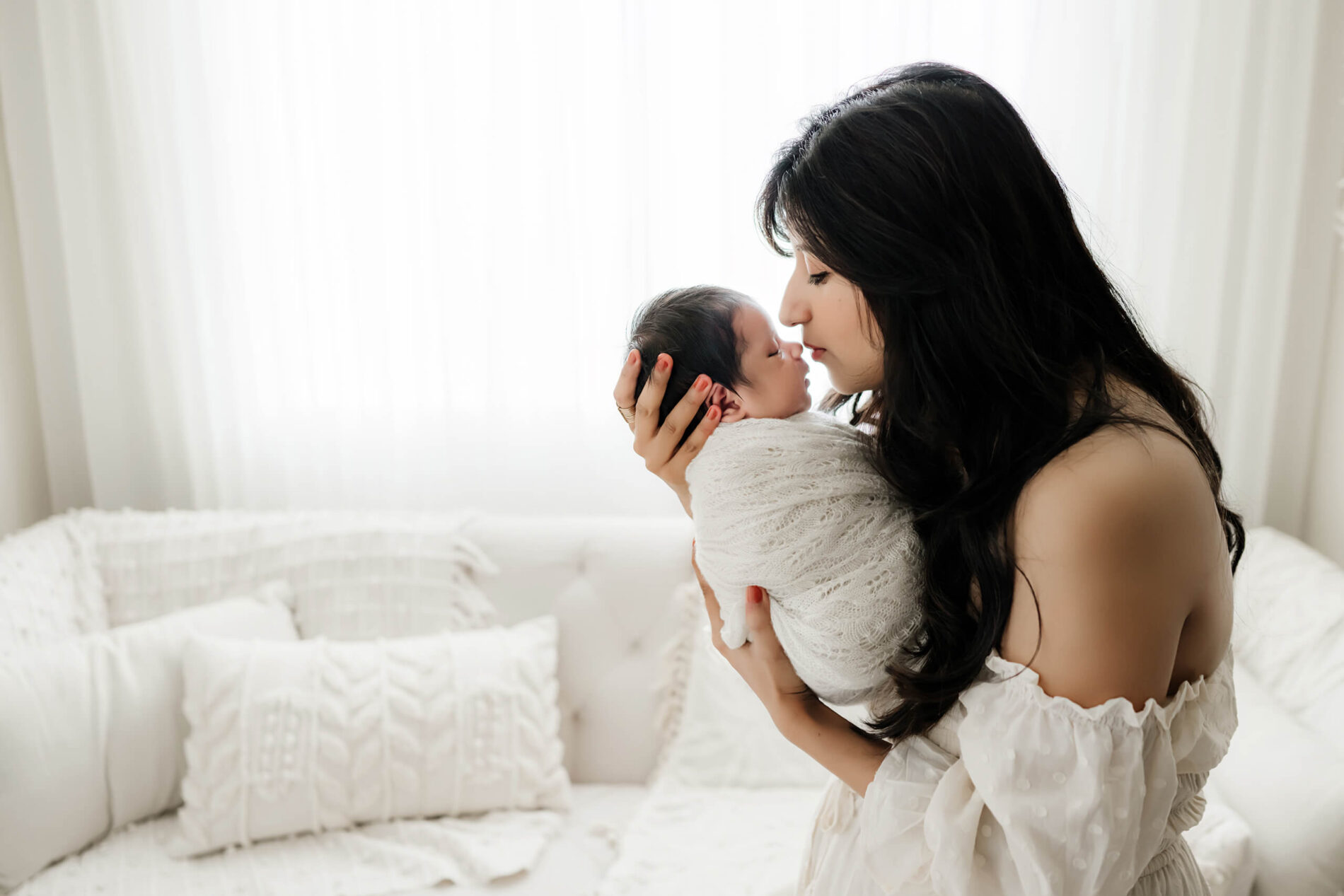 Unique newborn photography of a mom gently holding and kissing her son