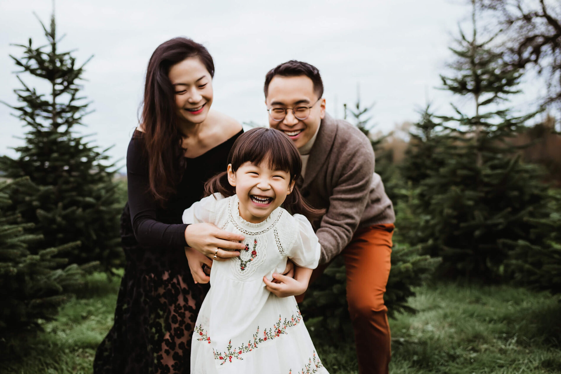 An elegantly dressed family having fun during a photoshoot at a Christmas tree farm near Seattle