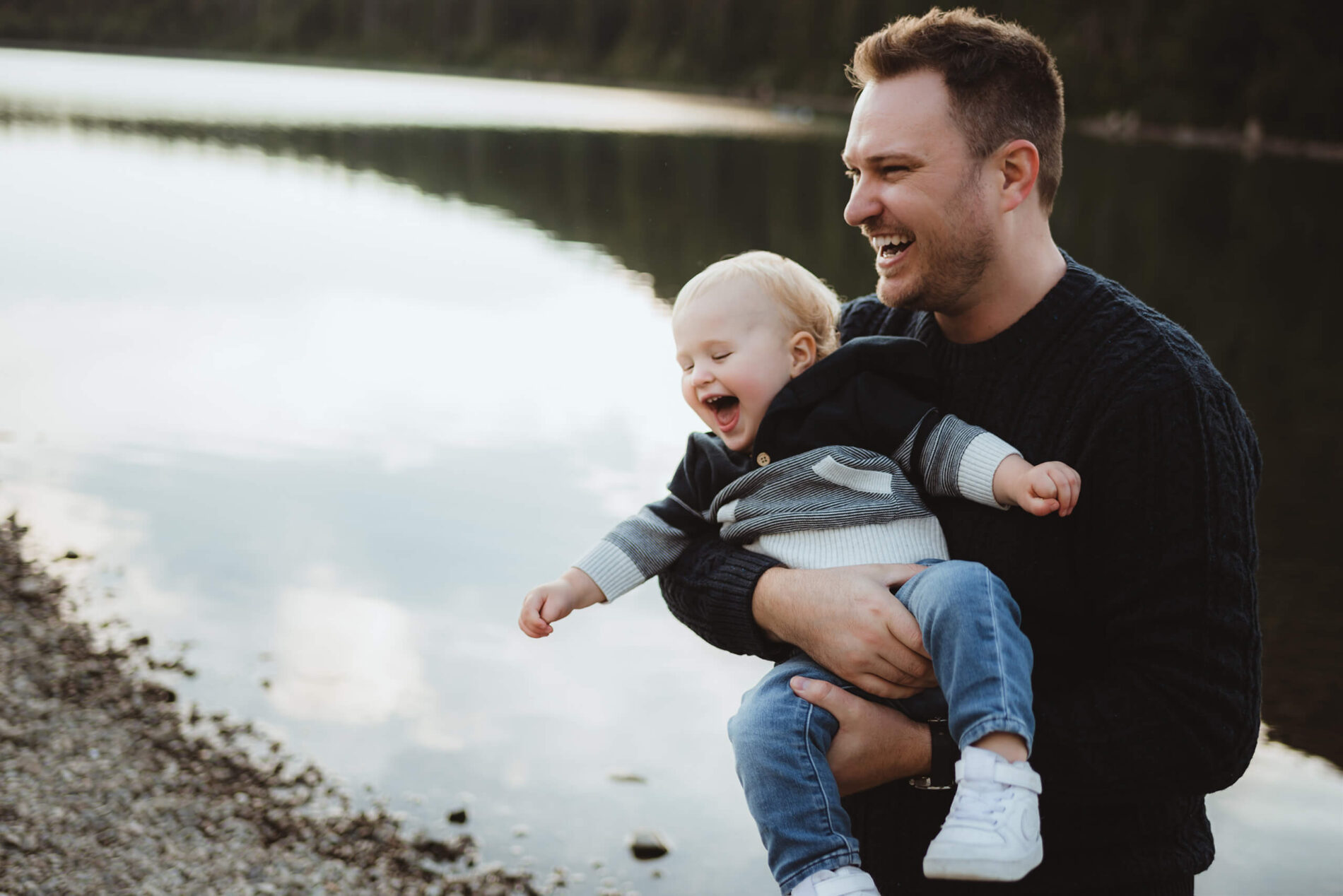 A moment during family photo session of dad playing with his son, both laughing
