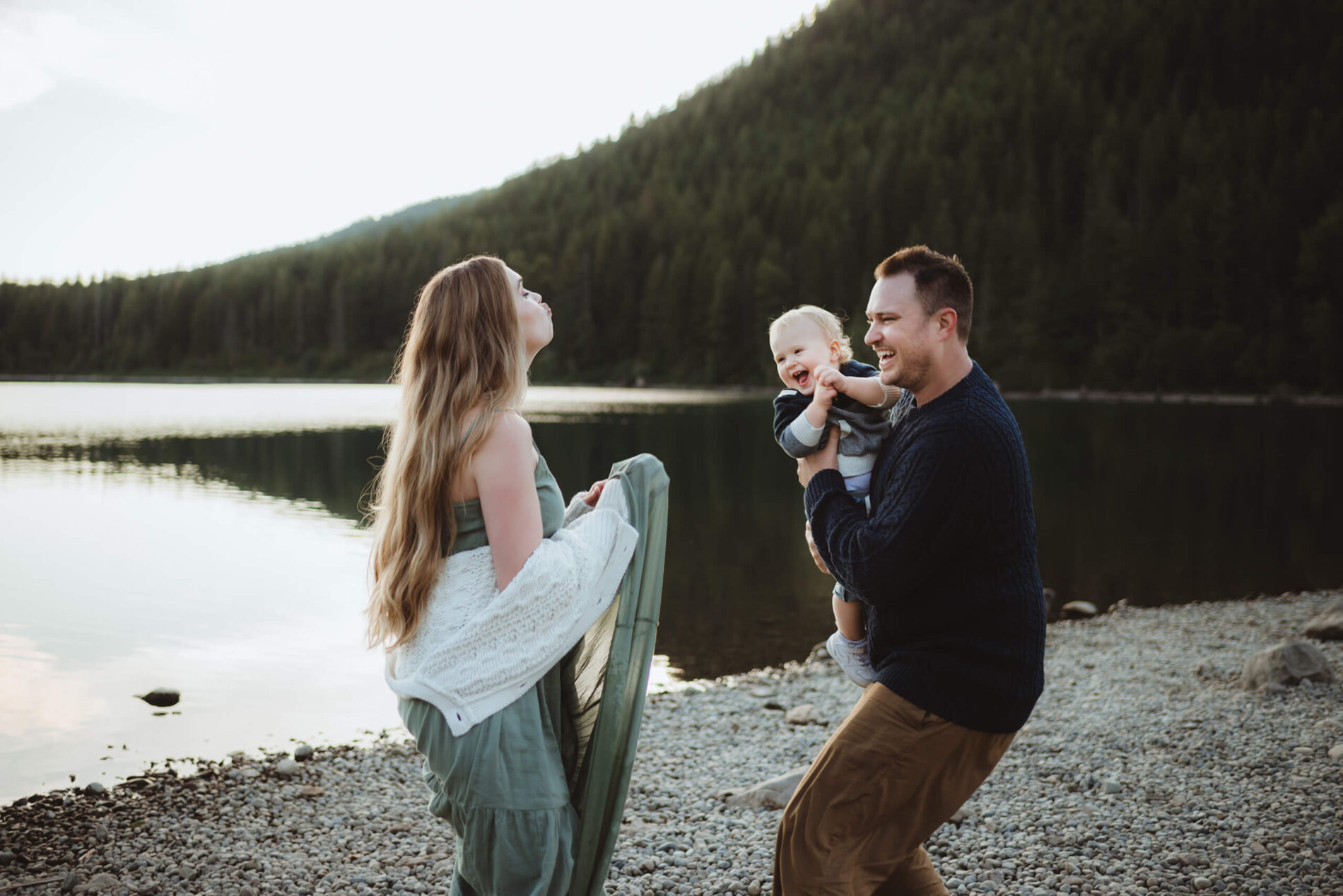 A playful moment during a family photoshoot at the beach with mountains in the background