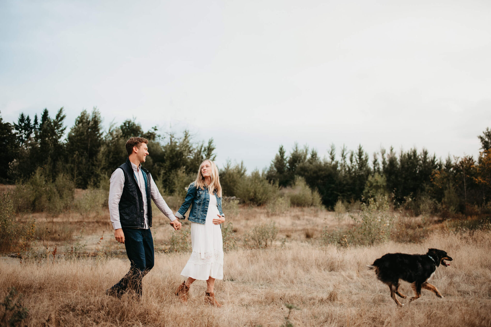 A young couple walking in a field during a maternity photography session in the Seattle area