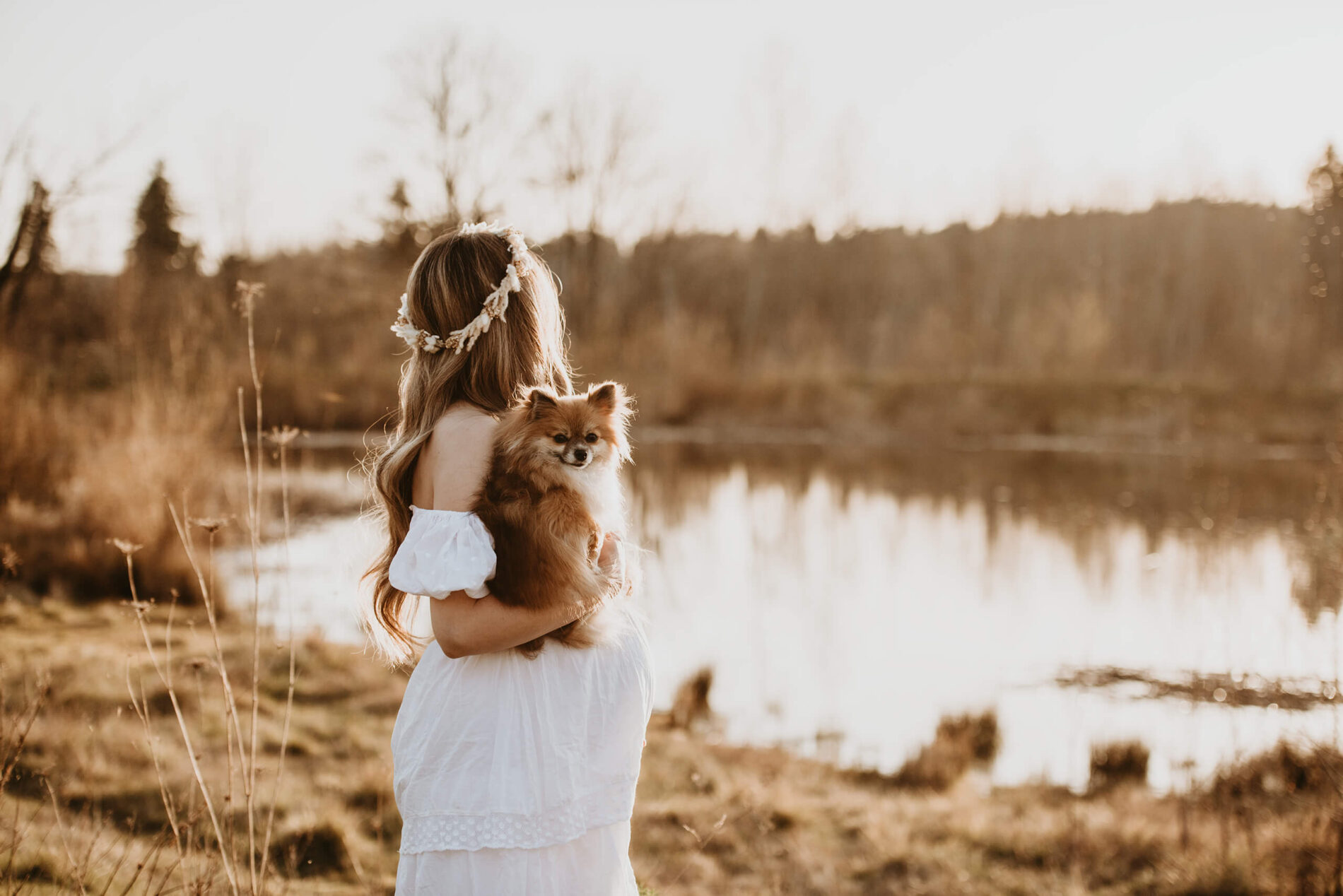 Single maternity photoshoot pose with mom holding her dog looking at a pond