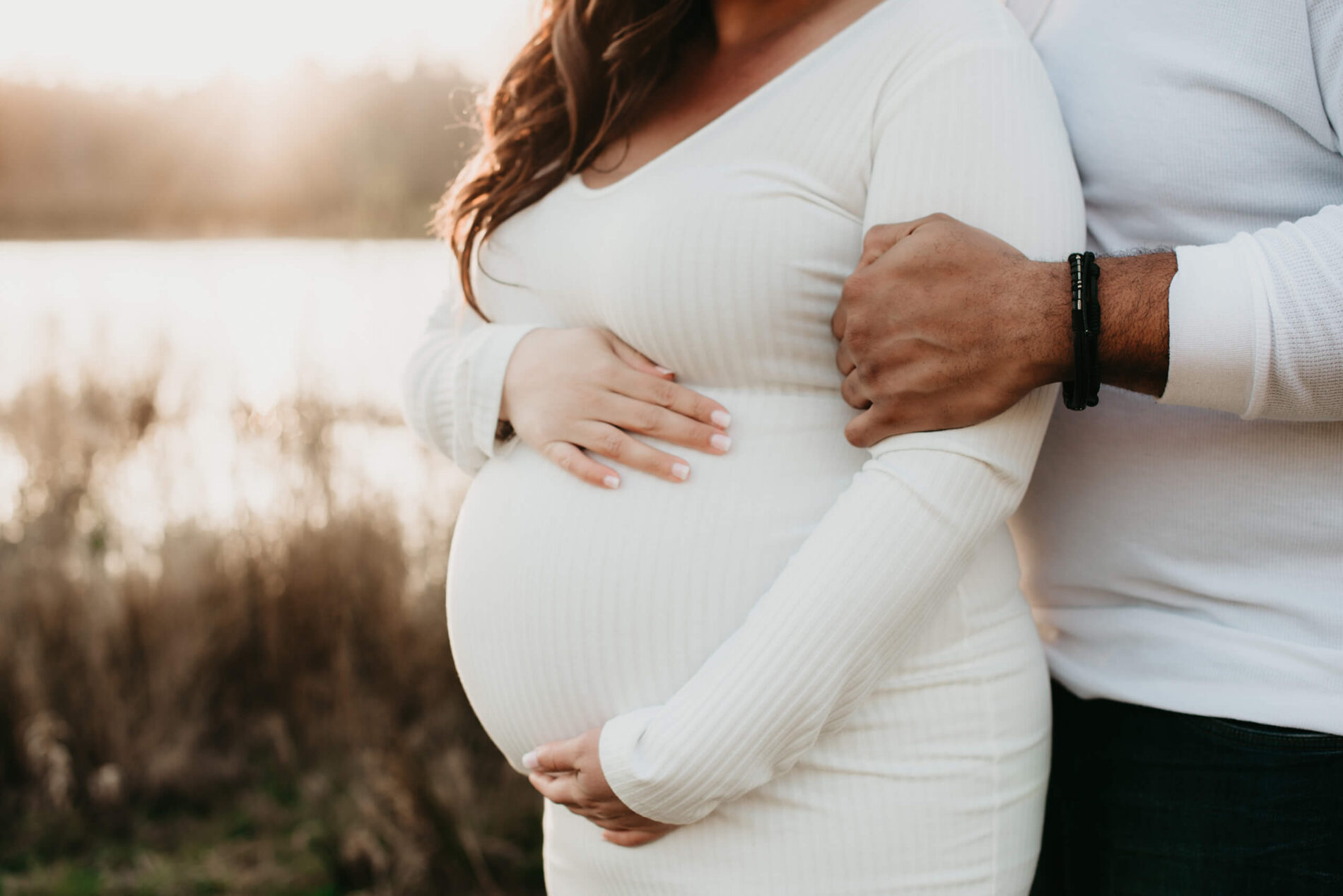 A couple maternity photoshoot in the Seattle area with a husband hugging his wife from behind who is holding her belly