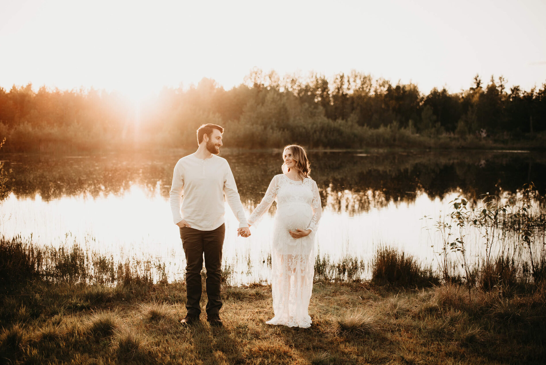 Pregnancy photo idea with the couple holding hands and looking at each other