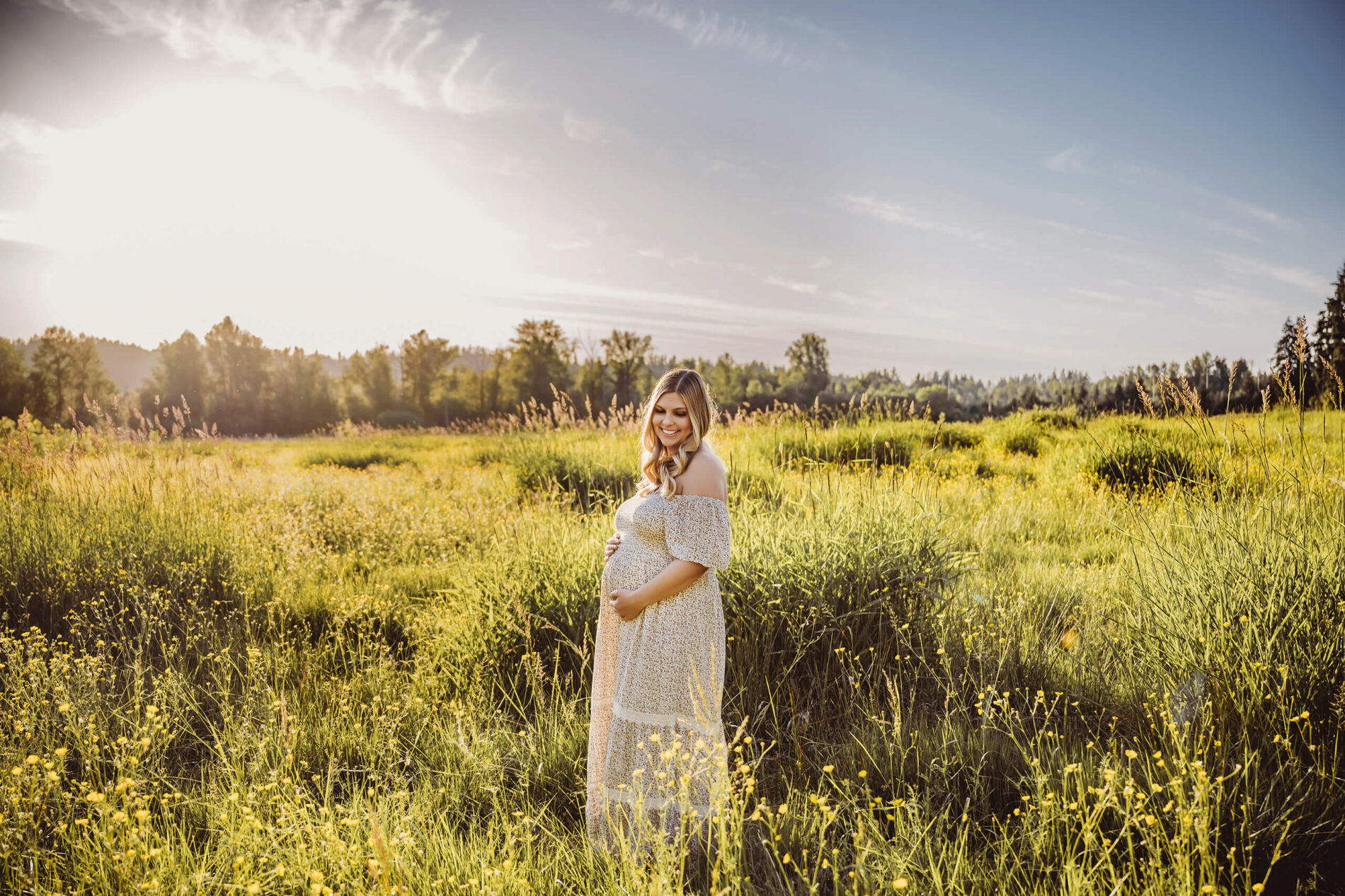 Single maternity photoshoot pose with mom smiling and holding her belly