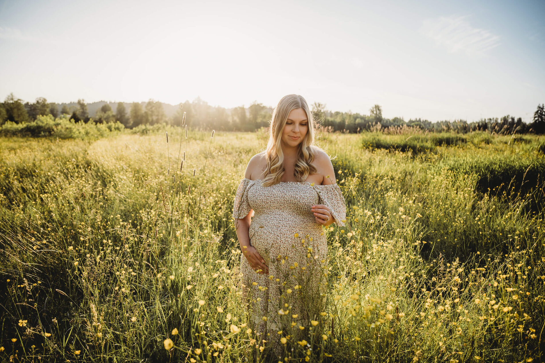 Single maternity photoshoot pose with mom holding her belly and smelling wild flowers