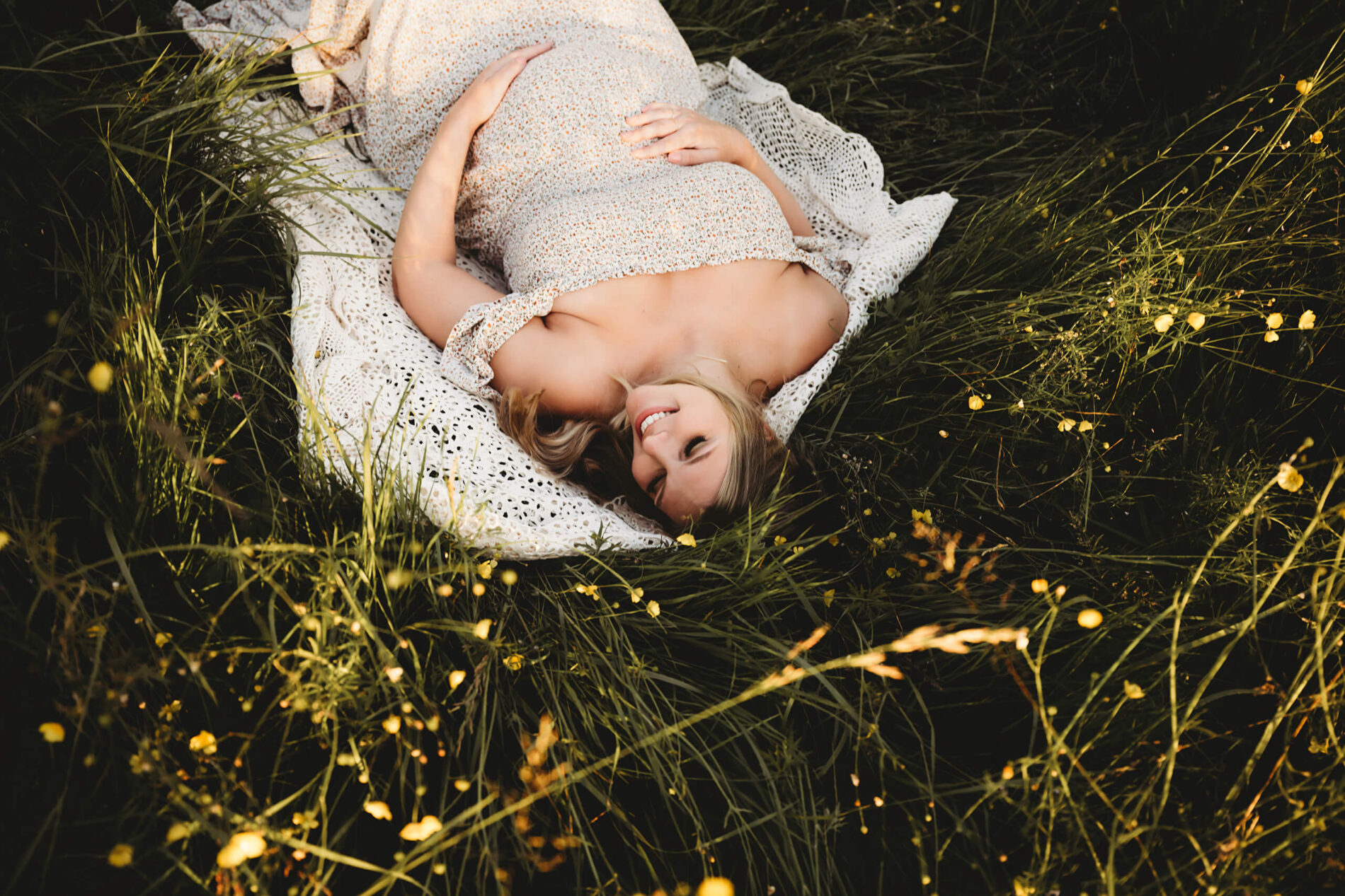 Maternity photo idea of a happy mom lying in a field of wild flowers