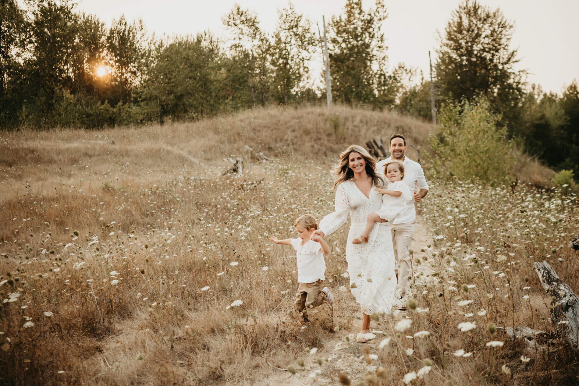 Family photo shoot in Redmond, WA - smiling mom, dad and two kids running through a field