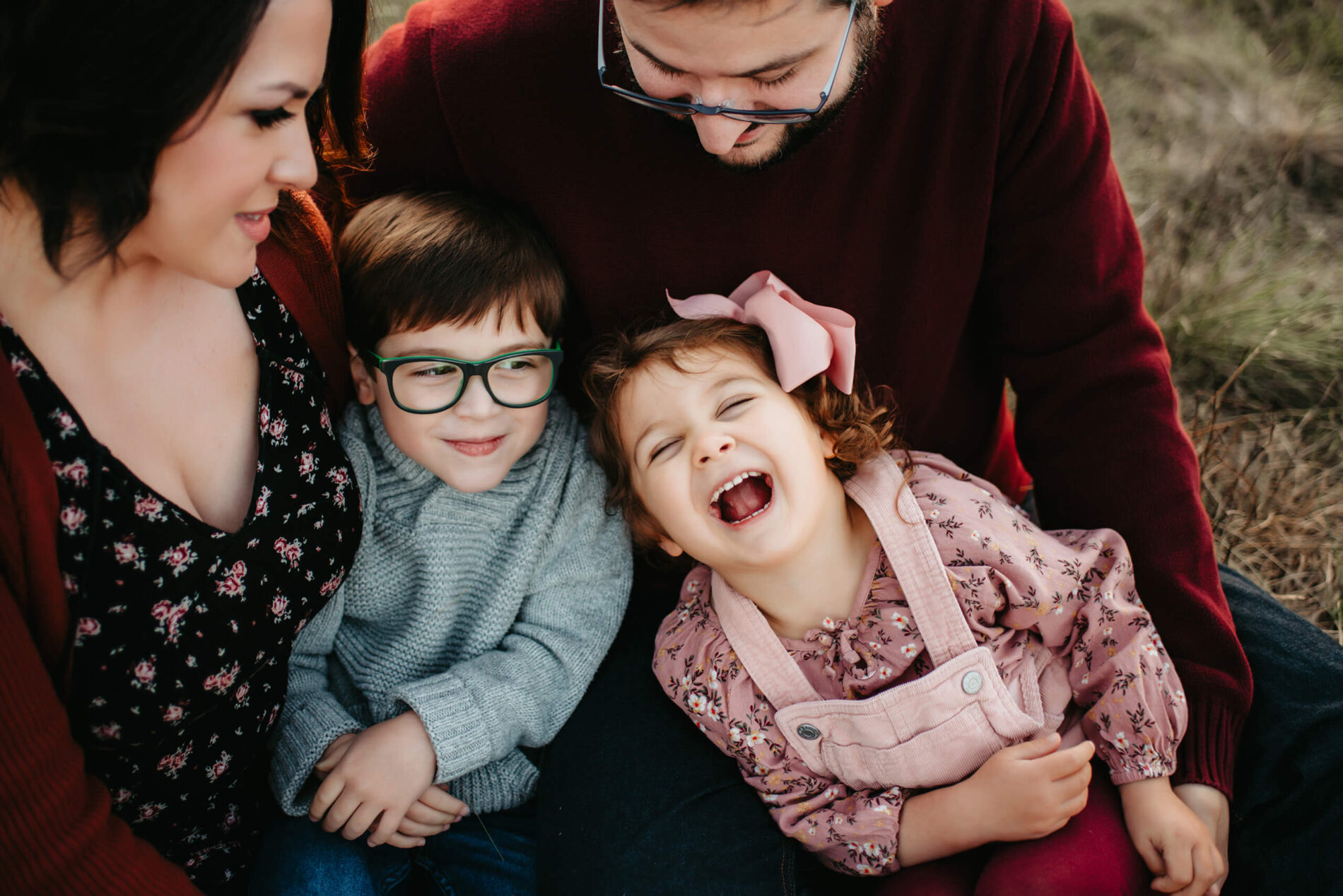 A family photo of mom dad cuddling with their son and daughter