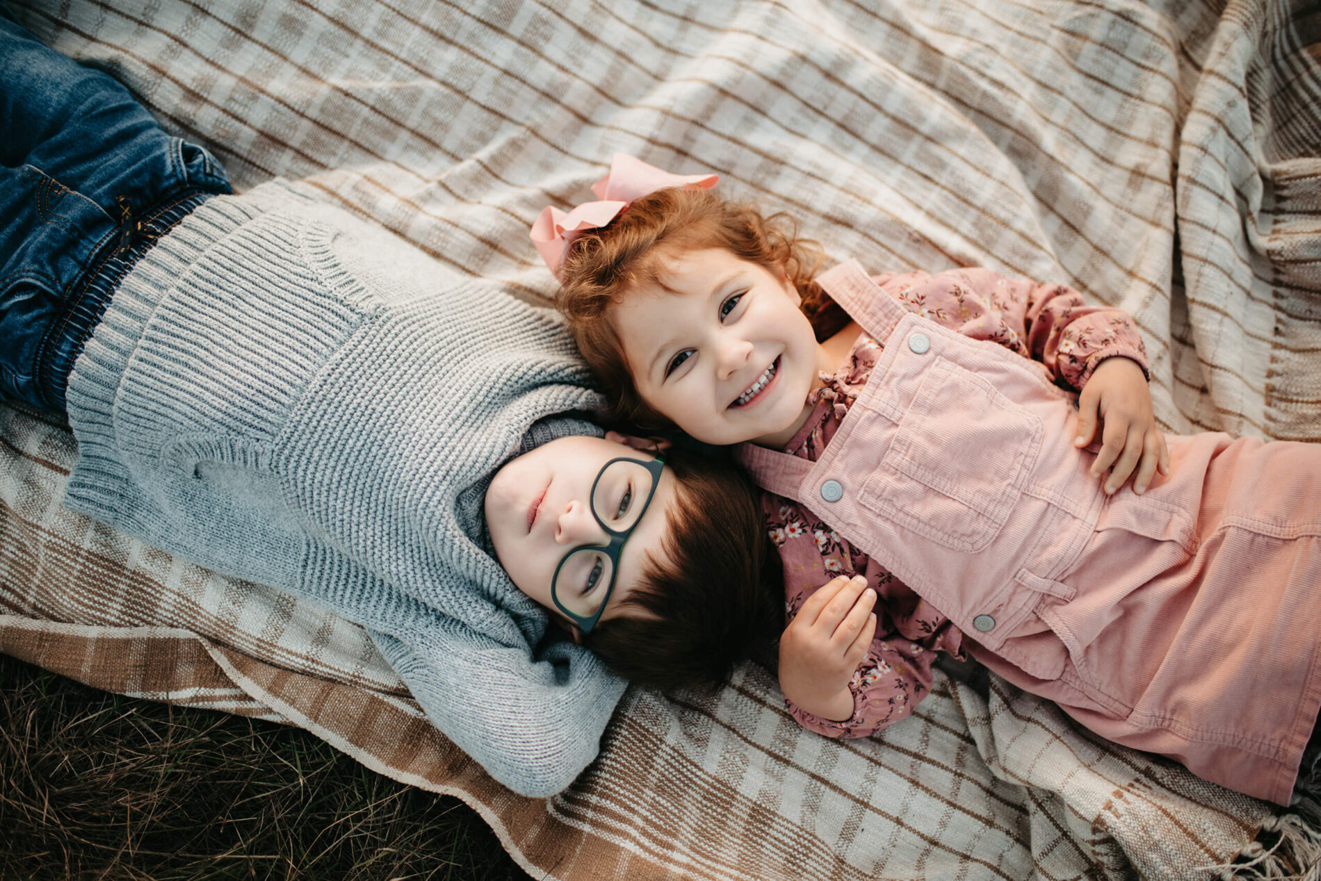 Family photo shoot of brother and sister lying on a blanket