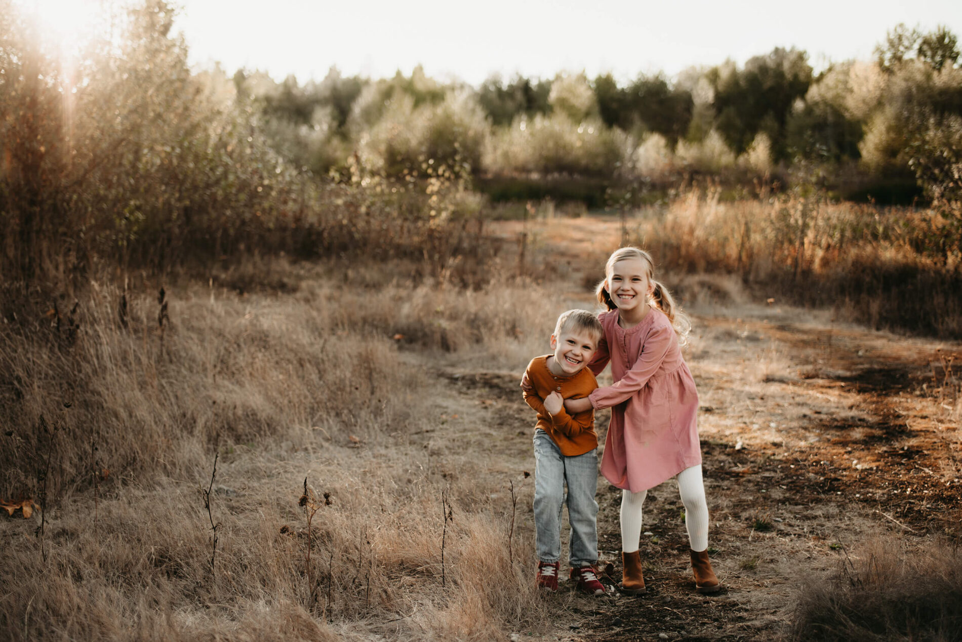 Family portrait of sister and brother in a filed of tall grass
