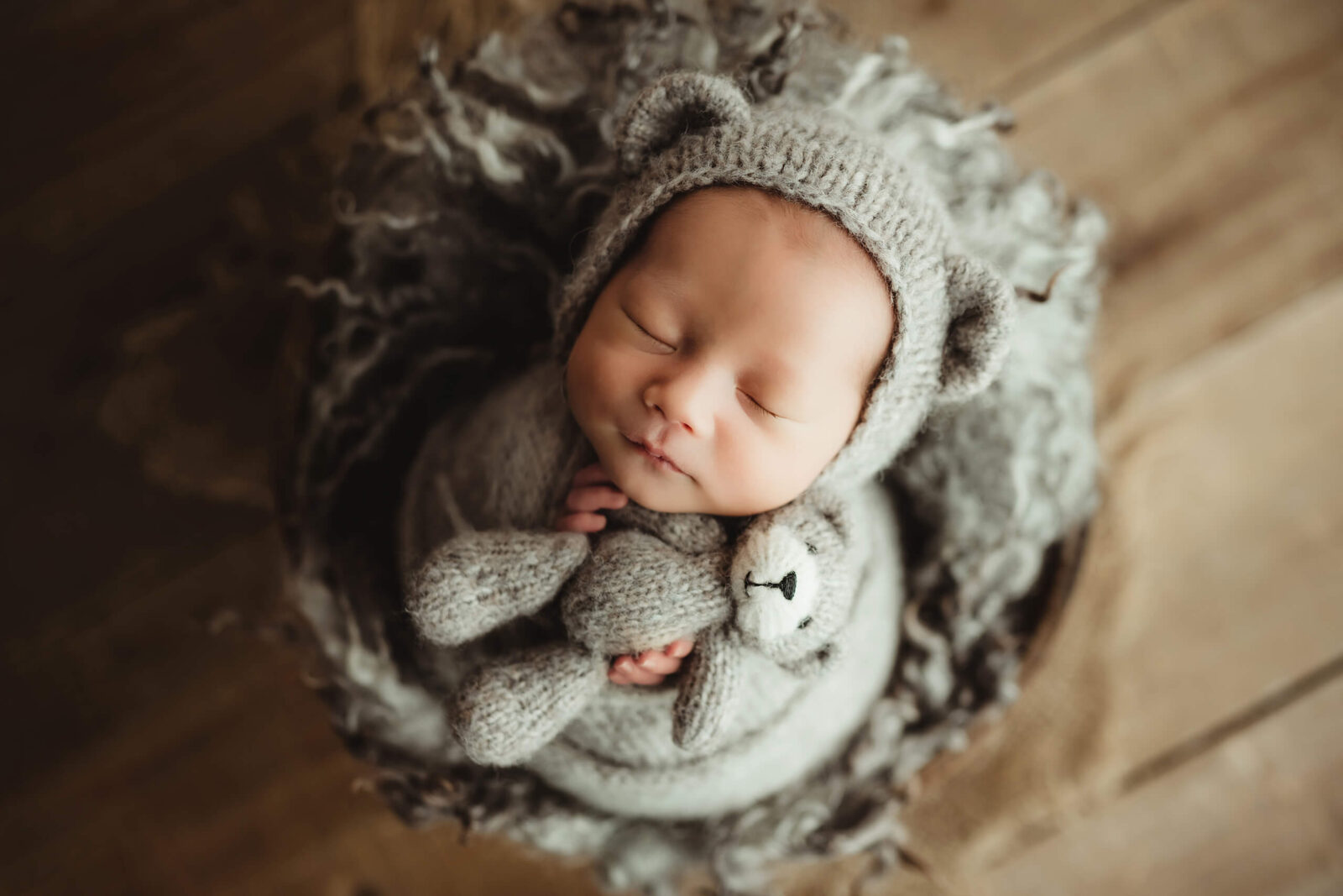 Newborn photography session with a baby boy sleeping in a basket and holding a stuffed toy