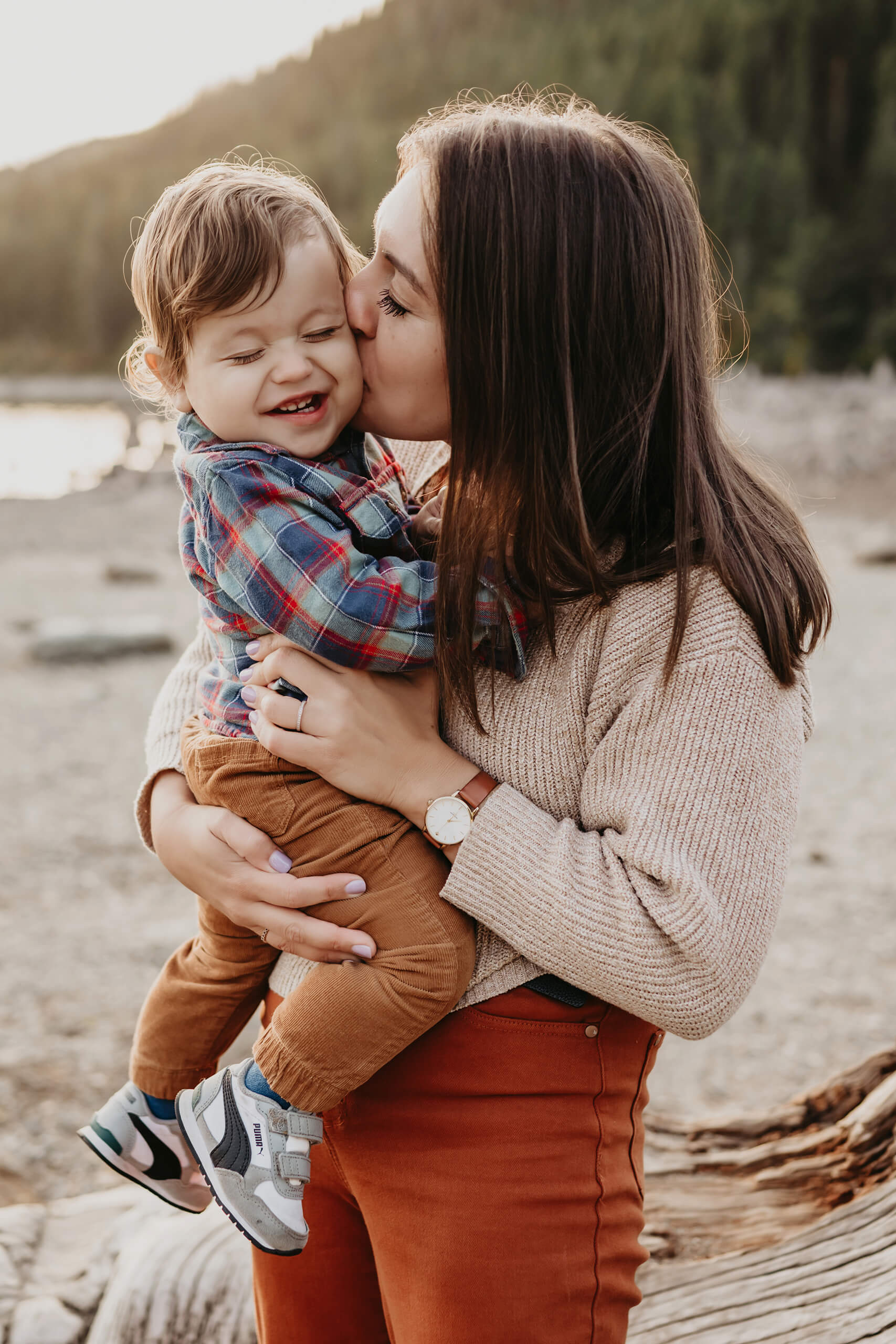 Lifestyle family photography of mom kissing her toddler son at a beach in Seattle area