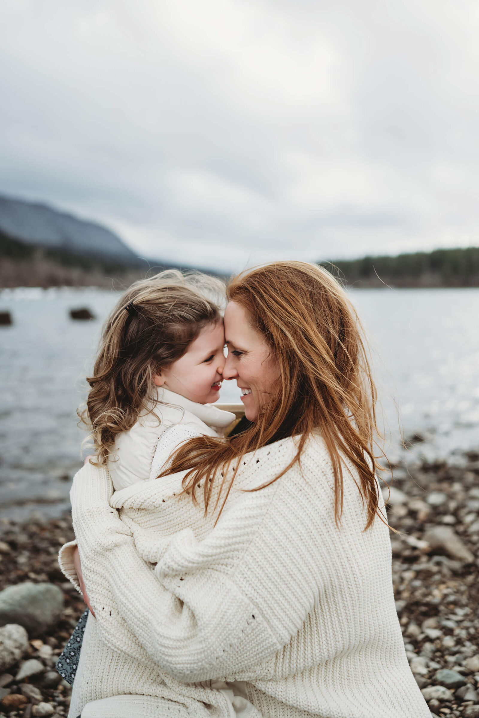 A moment during a family photoshoot of mom hugging her daughter on the beach at Rattlesnake Lake