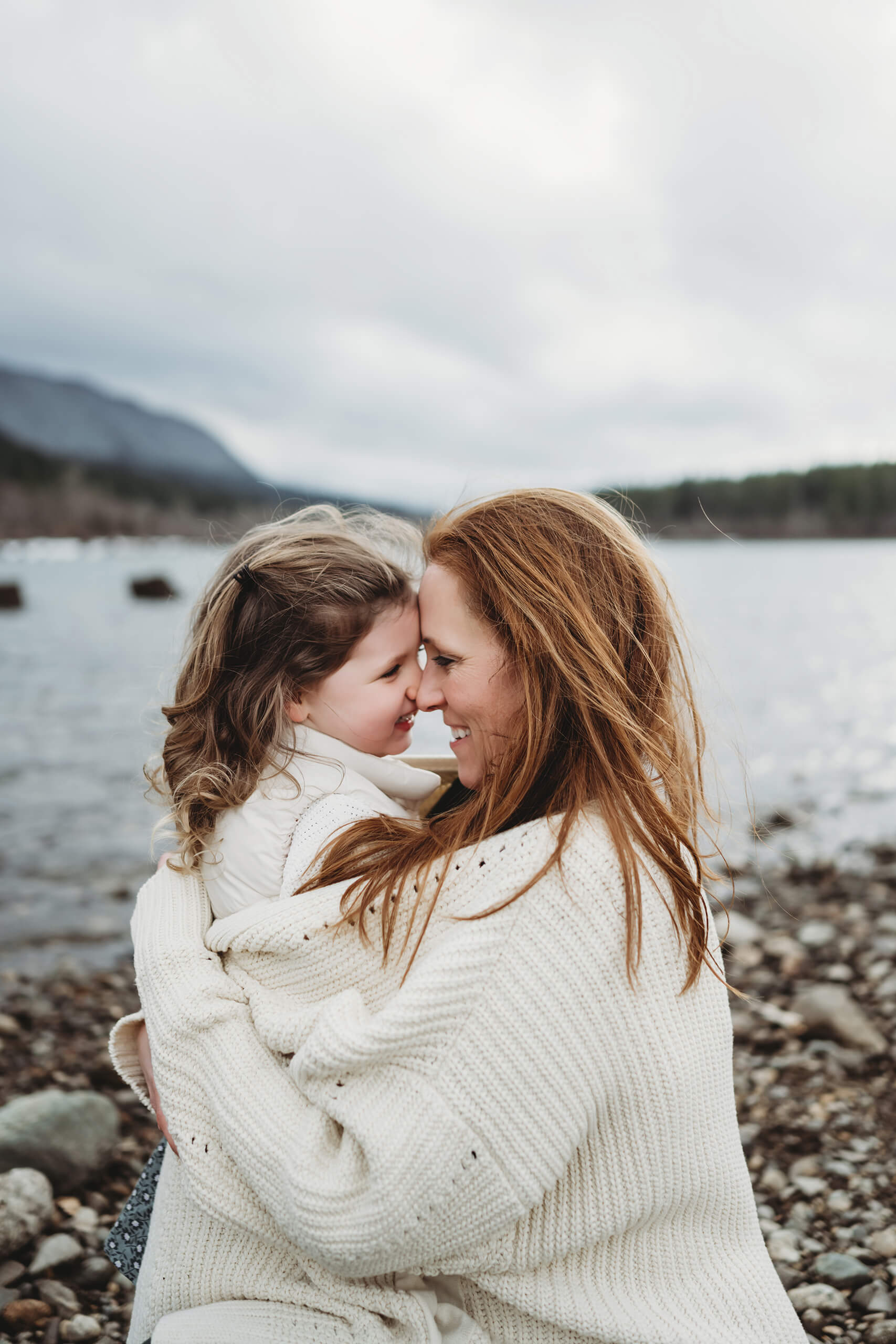A moment during a family photoshoot of mom hugging her daughter on the beach at Rattlesnake Lake