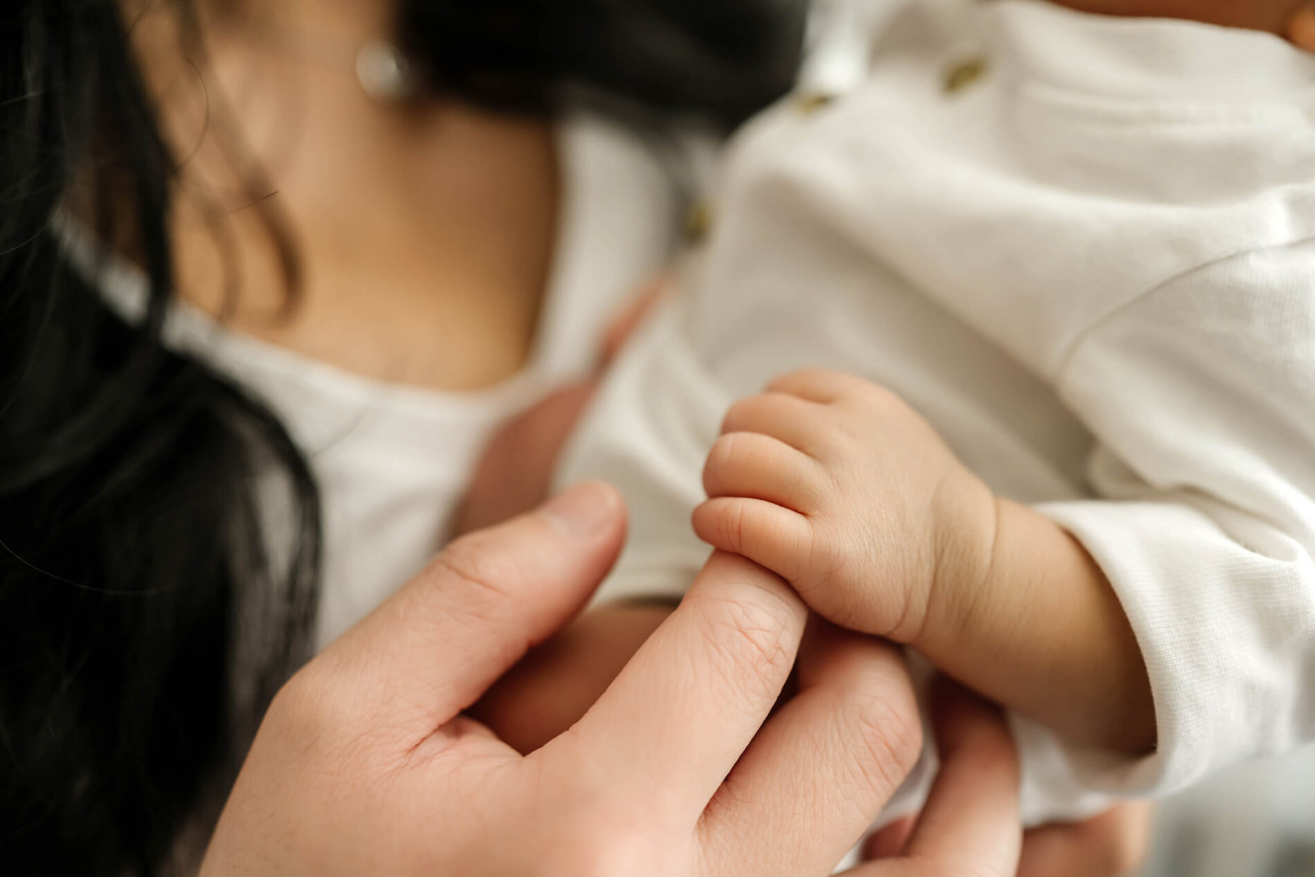Focus on mom holding newborn baby's hand during at home newborn photo shoot