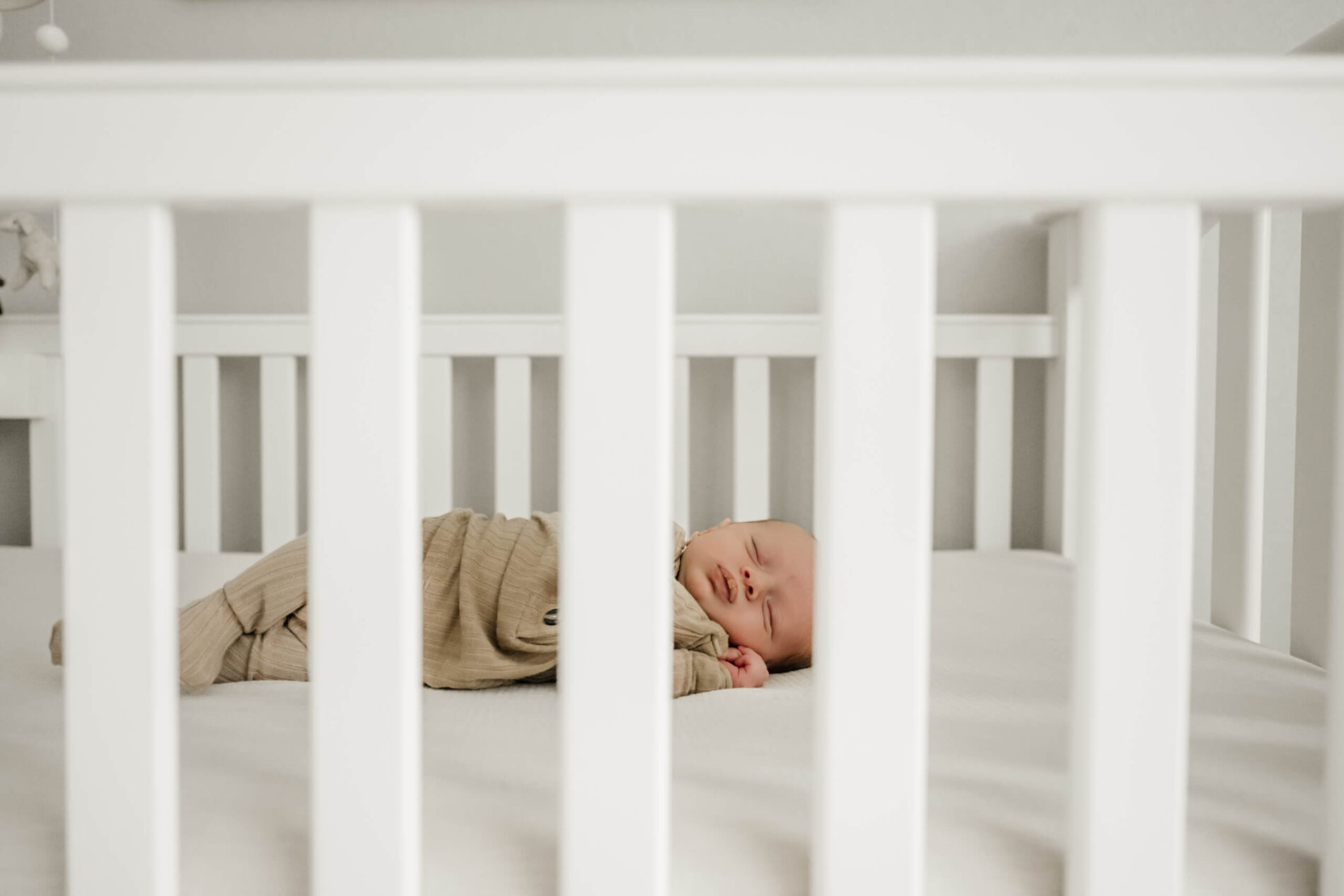Unposed newborn photography in a crib during in home photo shoot