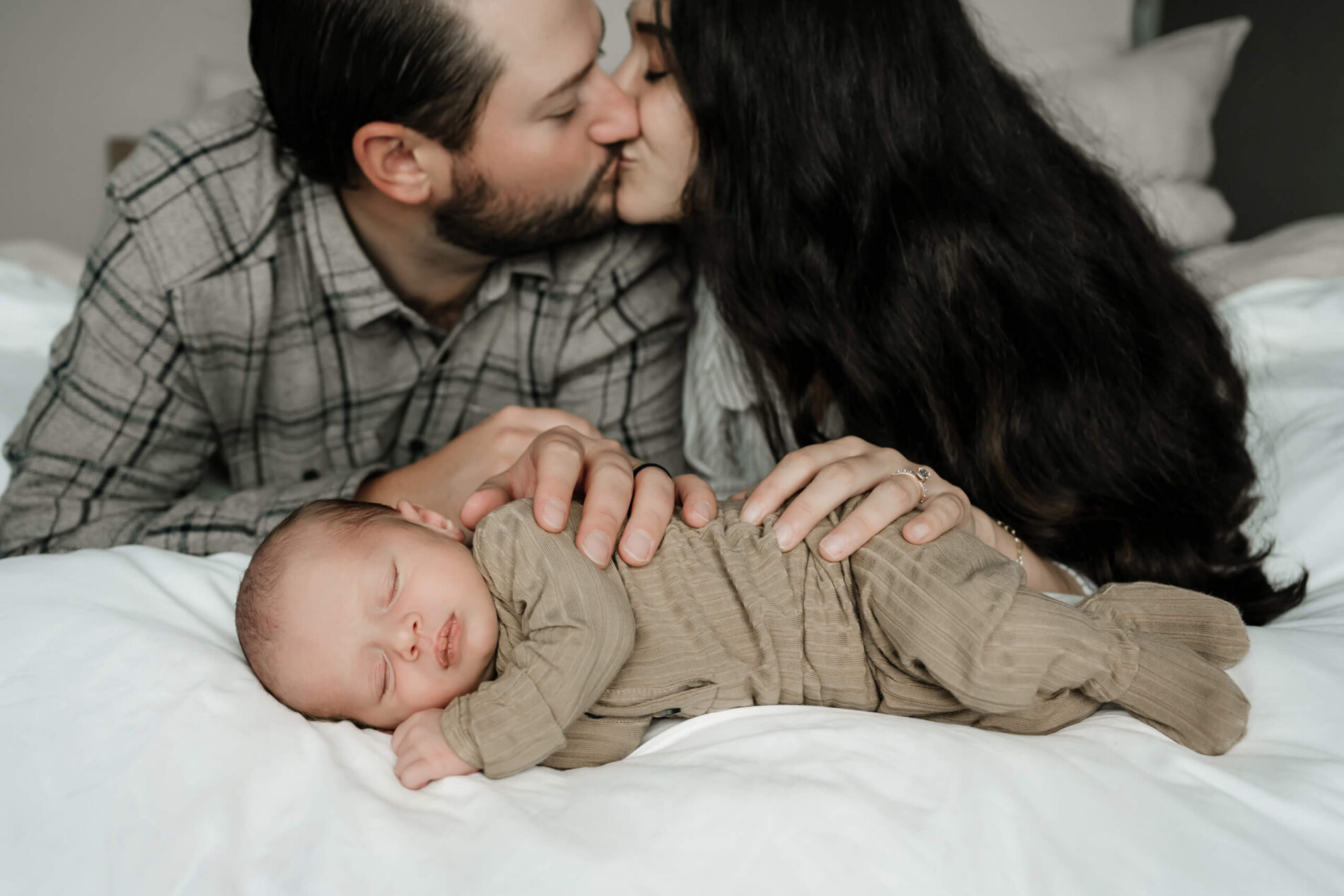 Family snuggling in a bedroom with newborn baby boy