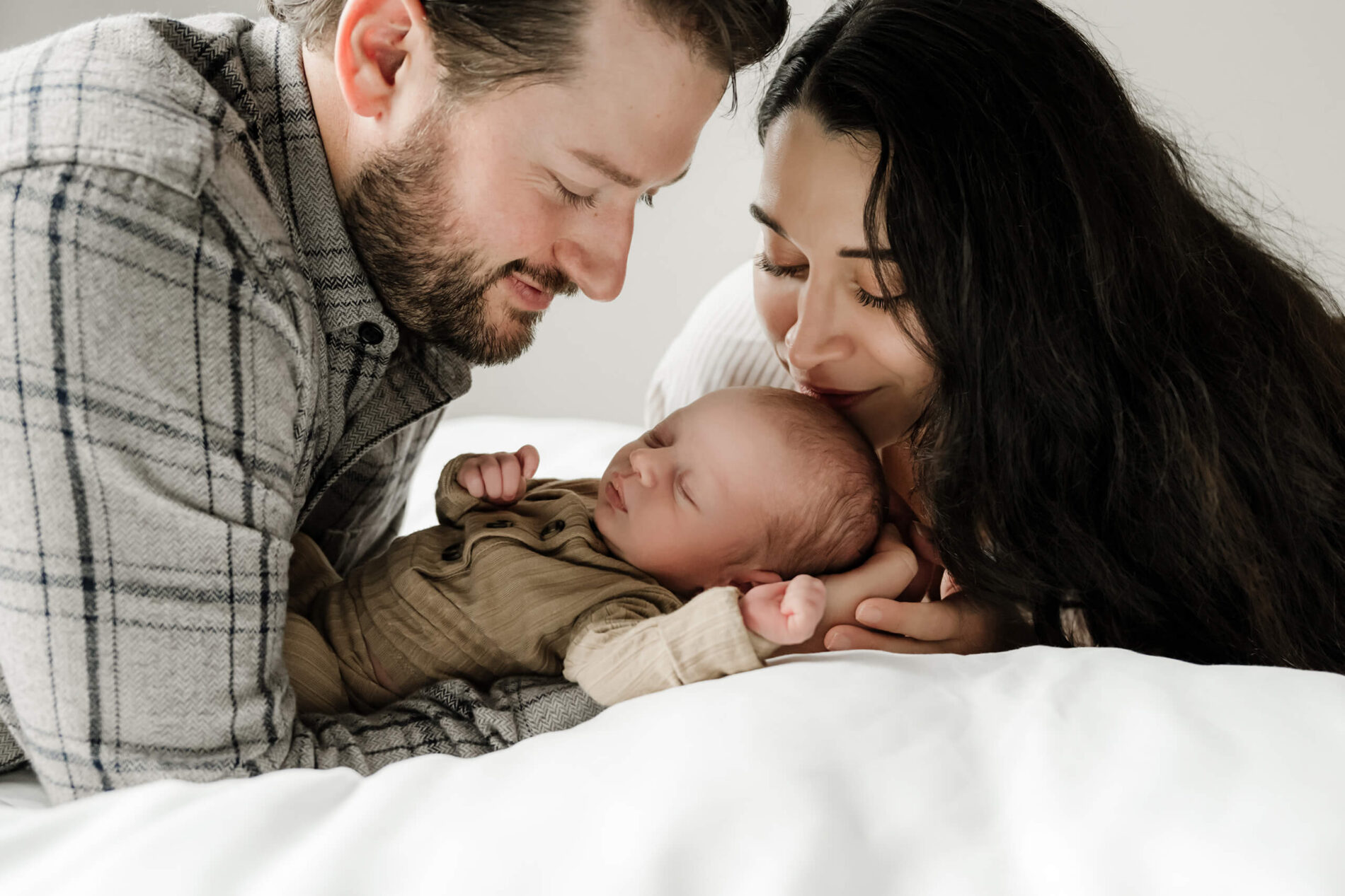 Family snuggling on a bed with newborn baby