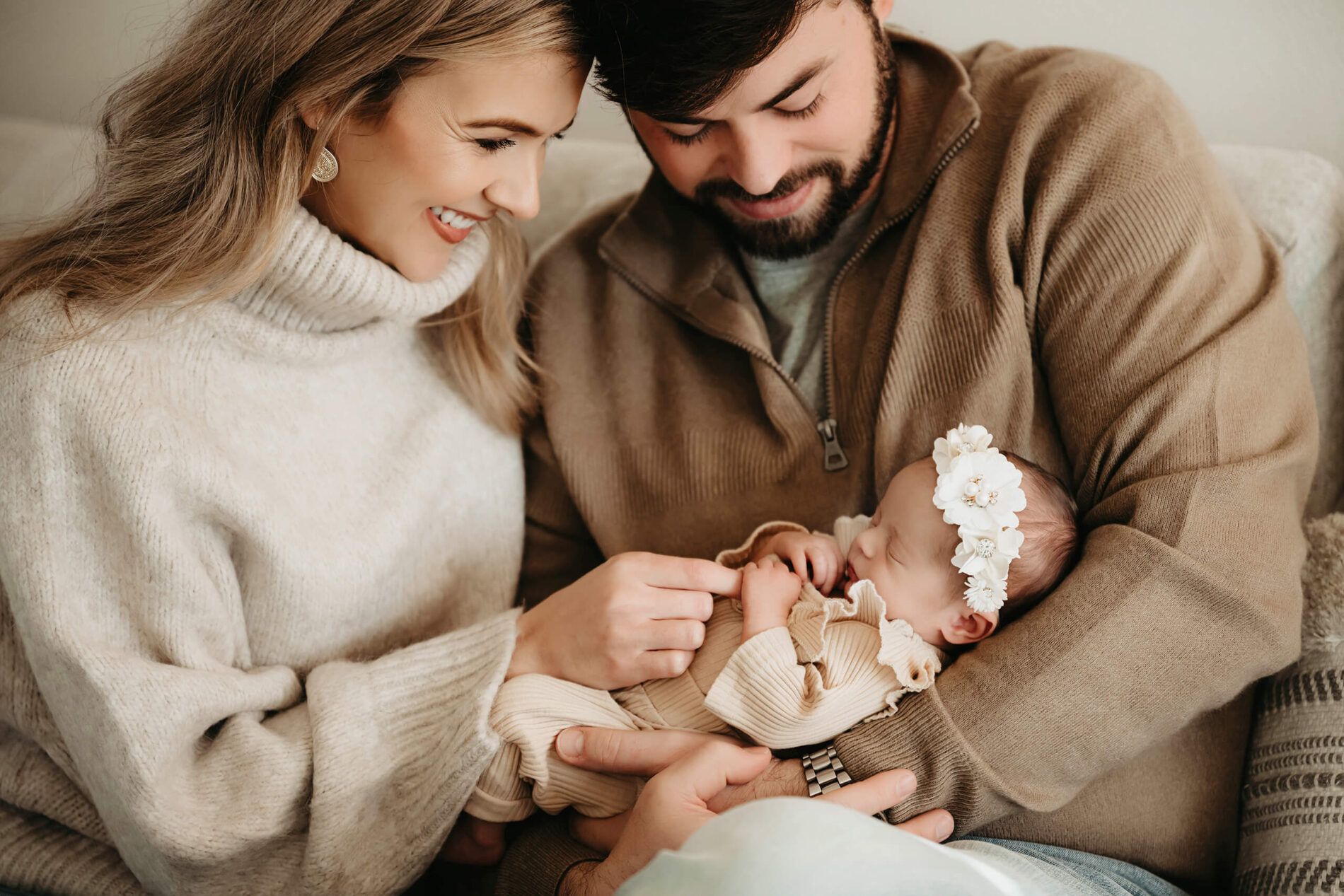 Family snuggling on a couch with newborn baby during newborn in home photo shoot in Seattle