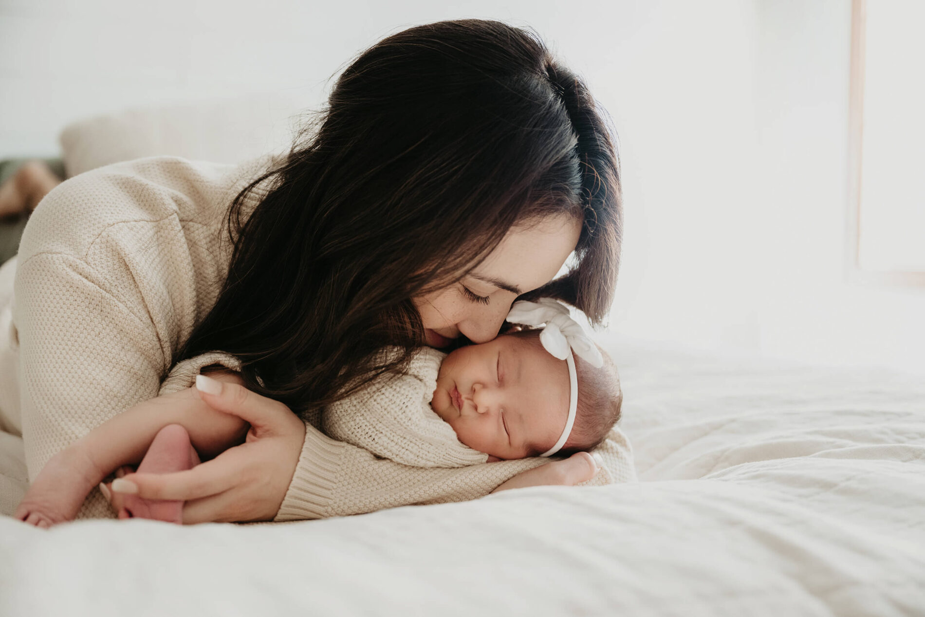 A moment during indoor newborn session of mom with her baby girl