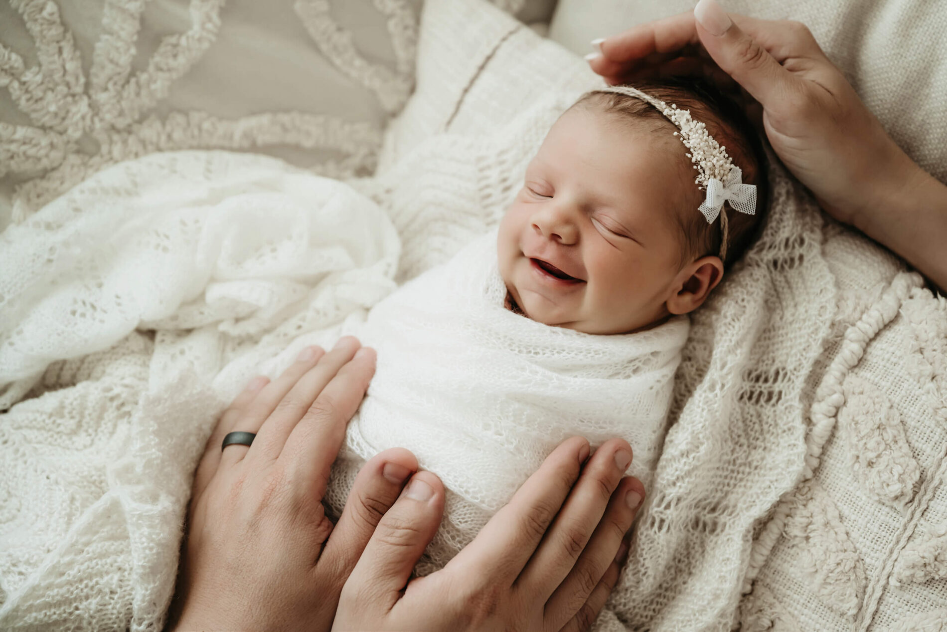 Cute photo of smiling baby girl during newborn photo shoot with parents