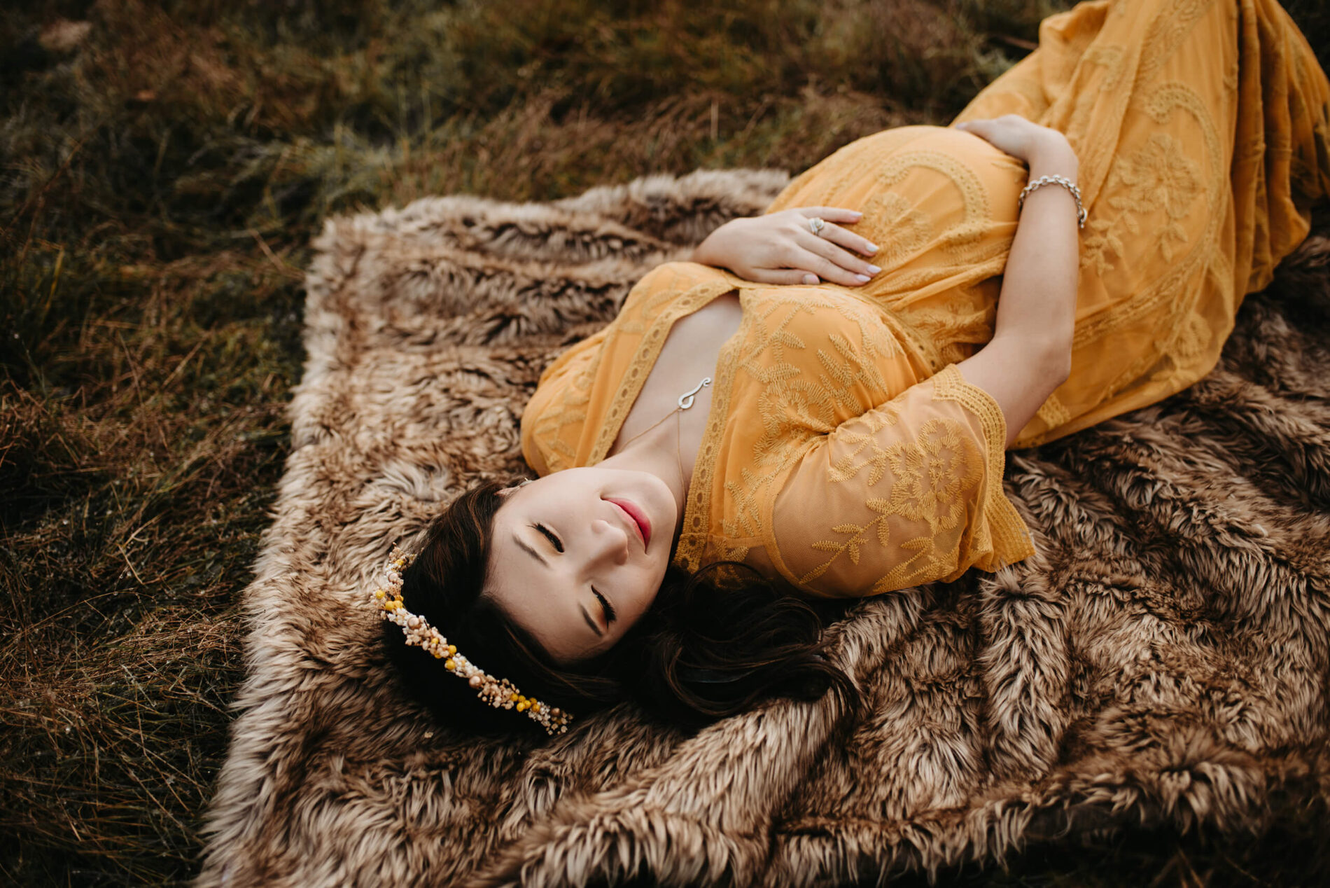 A woman lying on the ground during a winter maternity photo shoot