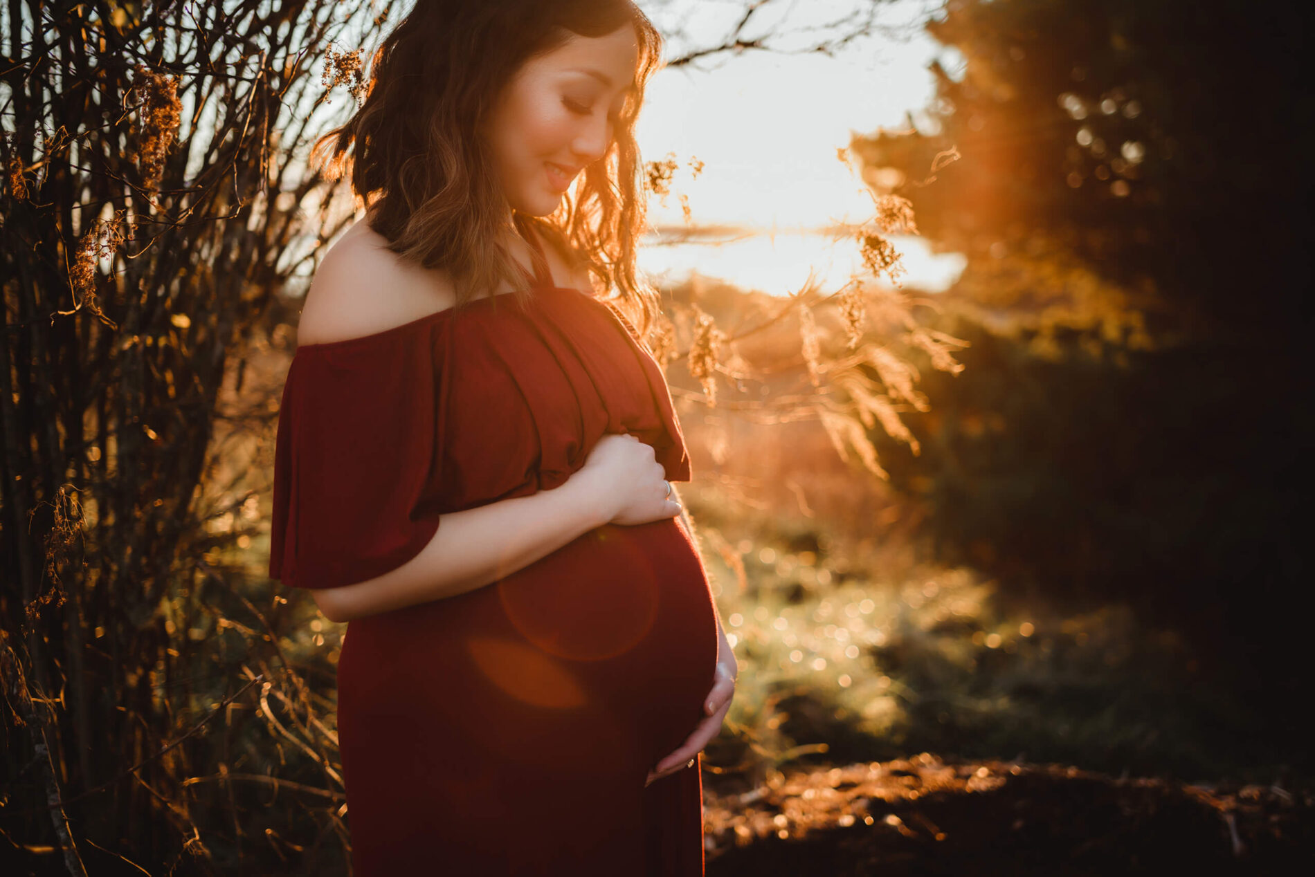 Woman posing during outdoor winter maternity photo shoot during beautiful sunset