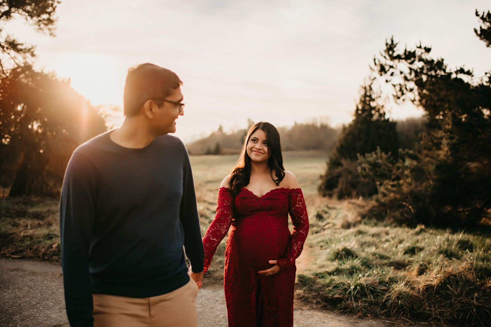 A happy couple holding hands during an outdoor winter maternity photo shoot
