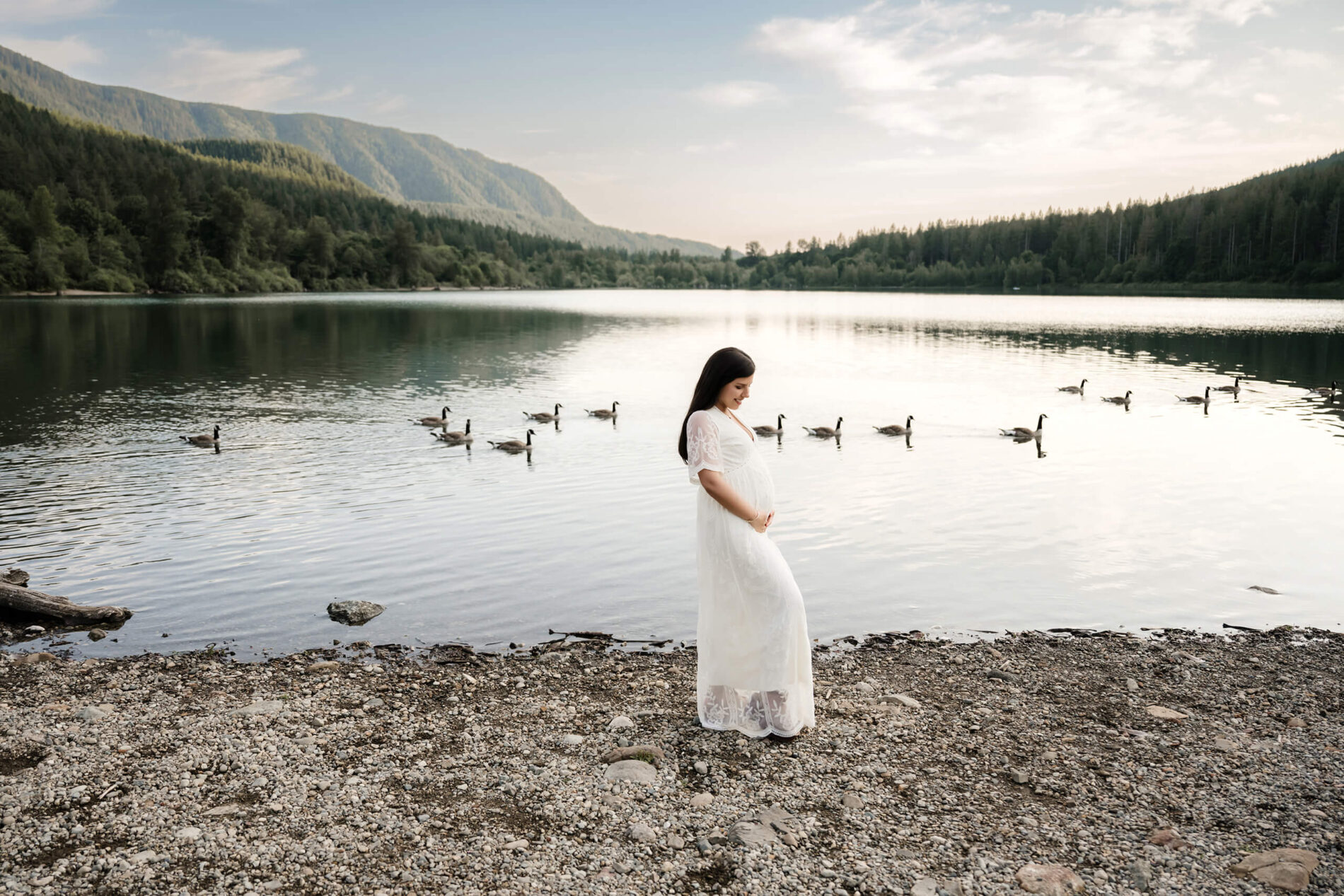 Pregnant woman posing during a maternity shoot in the Seattle area with mountains and lake in the background