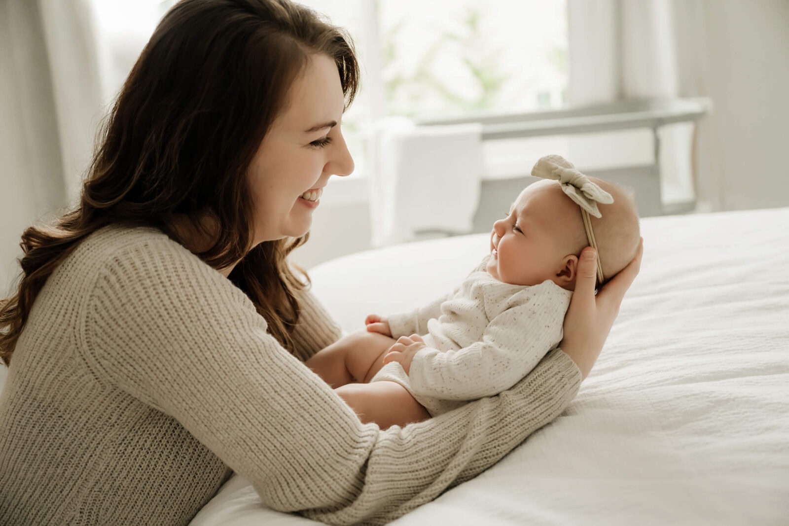 Mom and baby girl smiling at each other at a newborn photo shoot