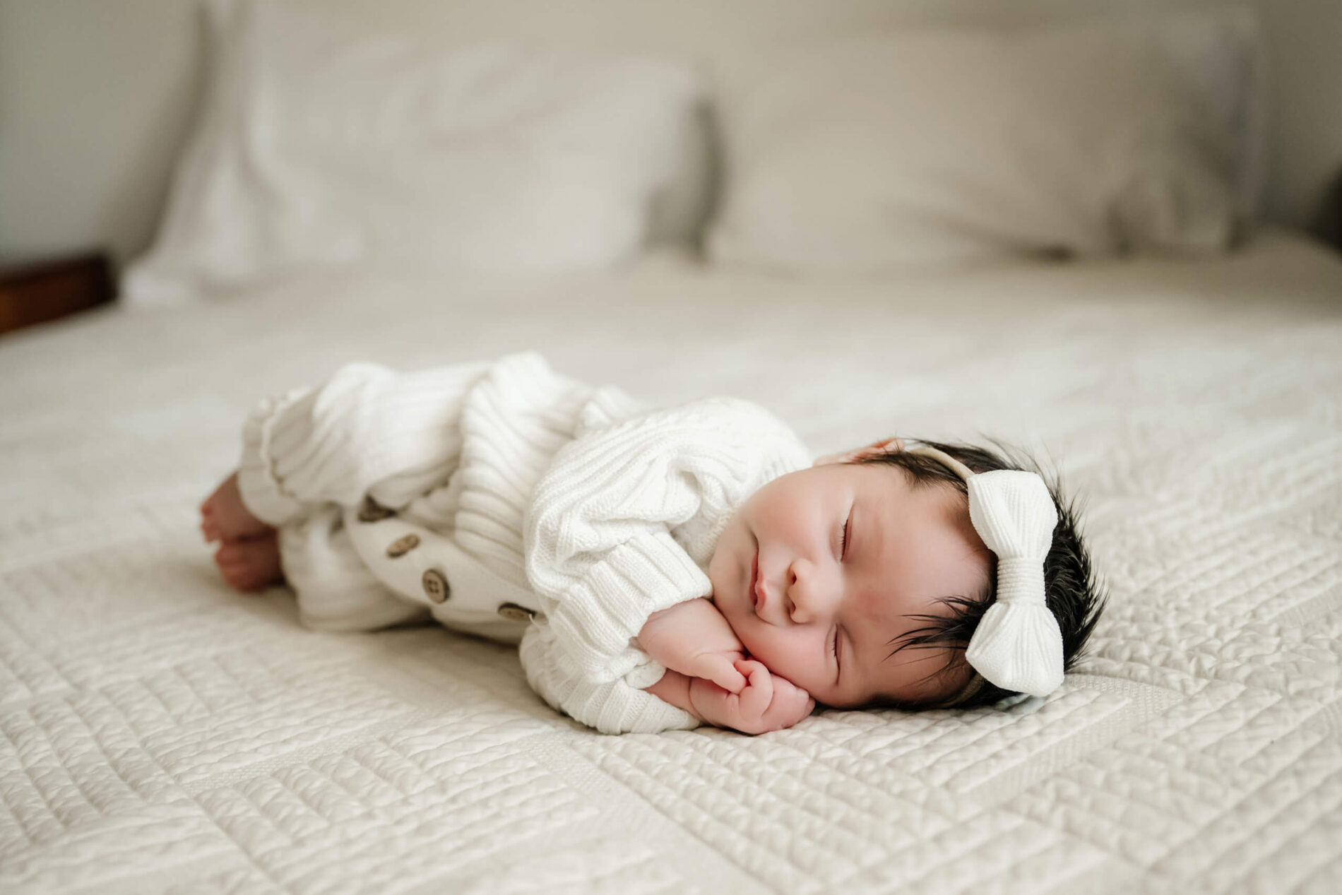 Baby girl in cute outfit sleeping on a bed during newborn photo shoot