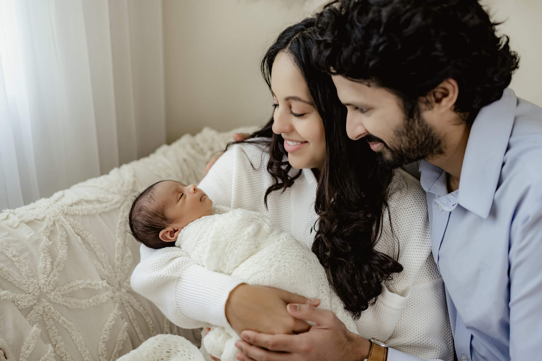 Natural family newborn photography, mom holding her son in her arms, with dad looking over