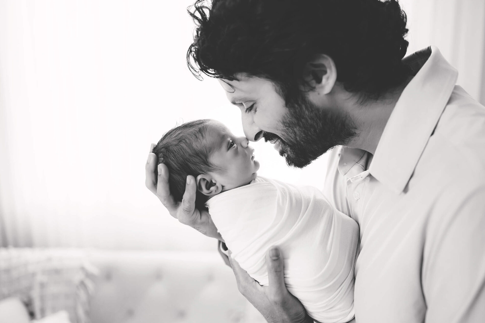 Black and white newborn photography, dad holding his son, their noses gently touching