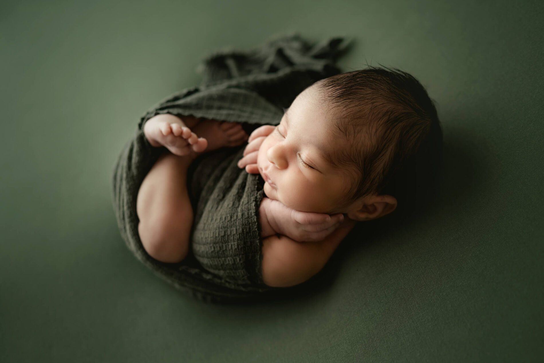 Unique newborn photography in Seattle, sleeping baby boy wrapped in green blanket