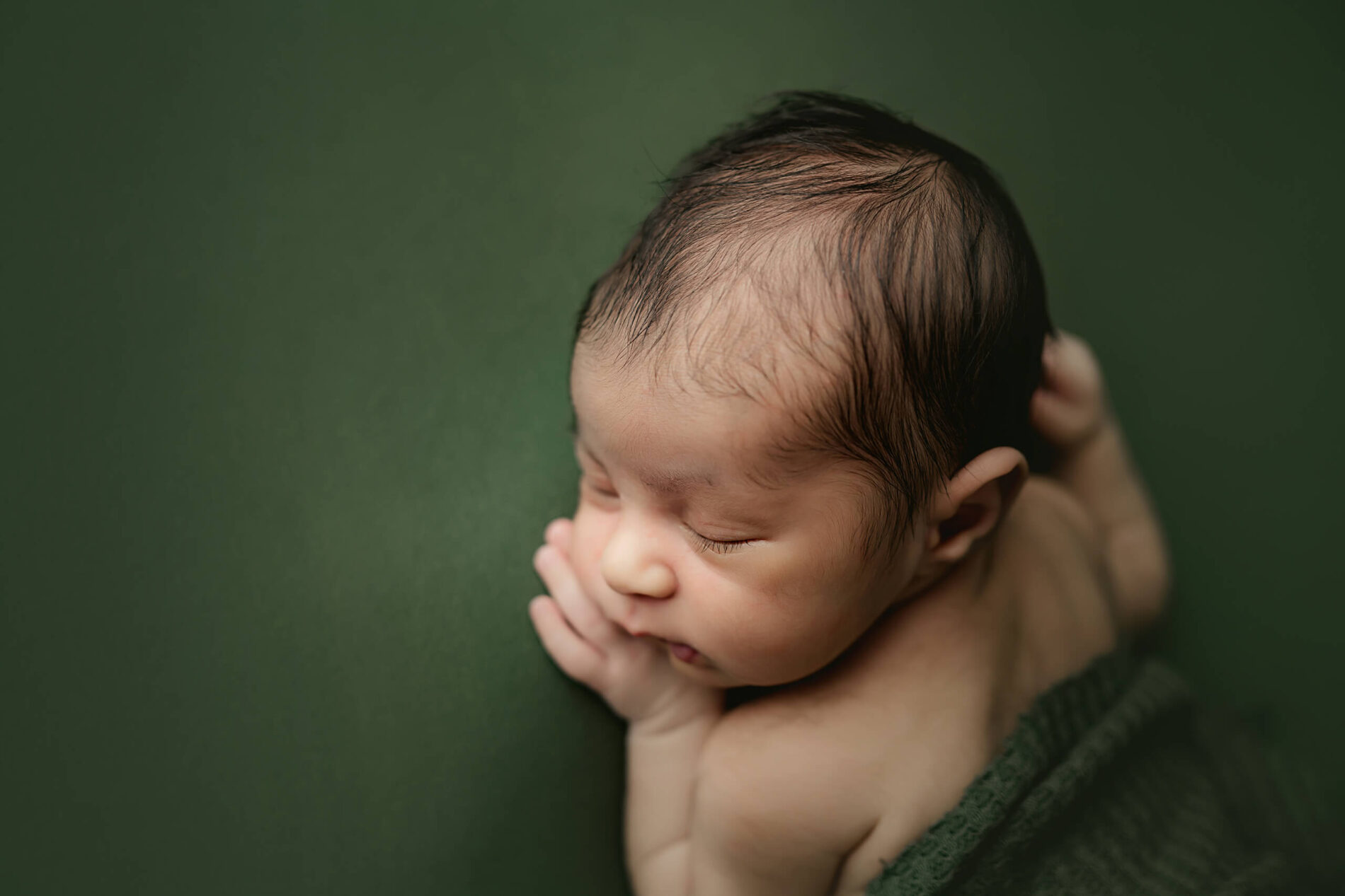 Newborn photography in Seattle, posed sleeping baby boy on green background