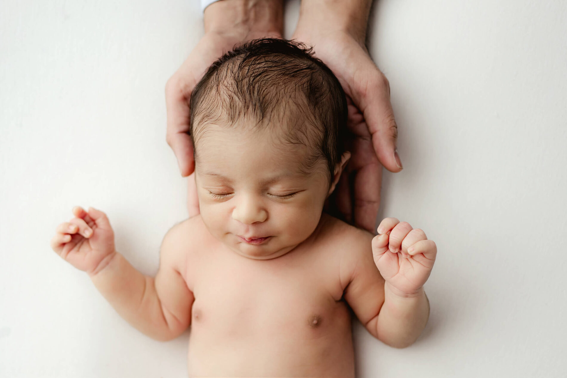 Newborn photography, close-up on dad's hands and baby's face