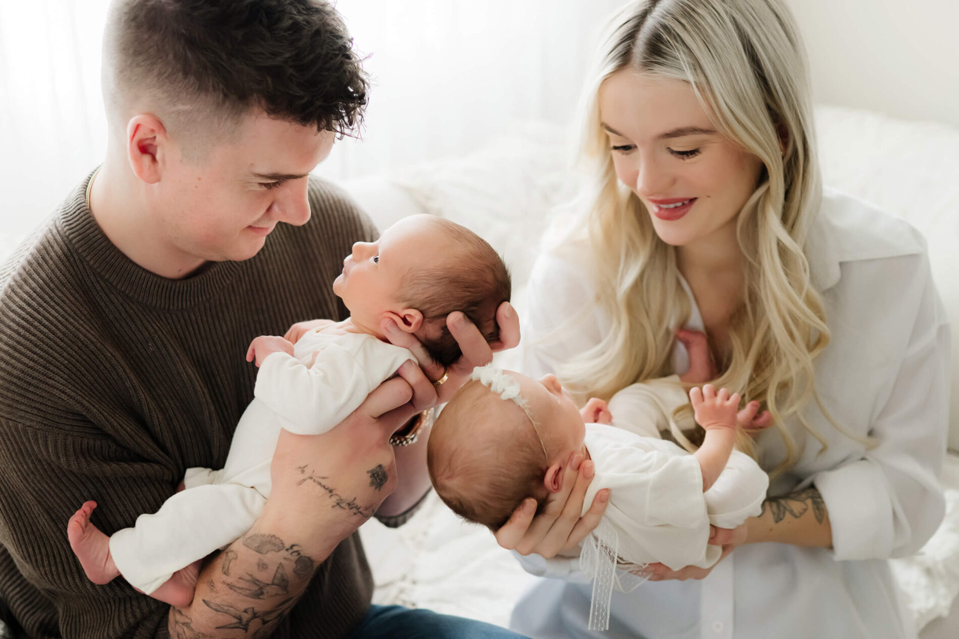 Twin newborn photography with parents, dad holding baby boy, and mom holding baby girl