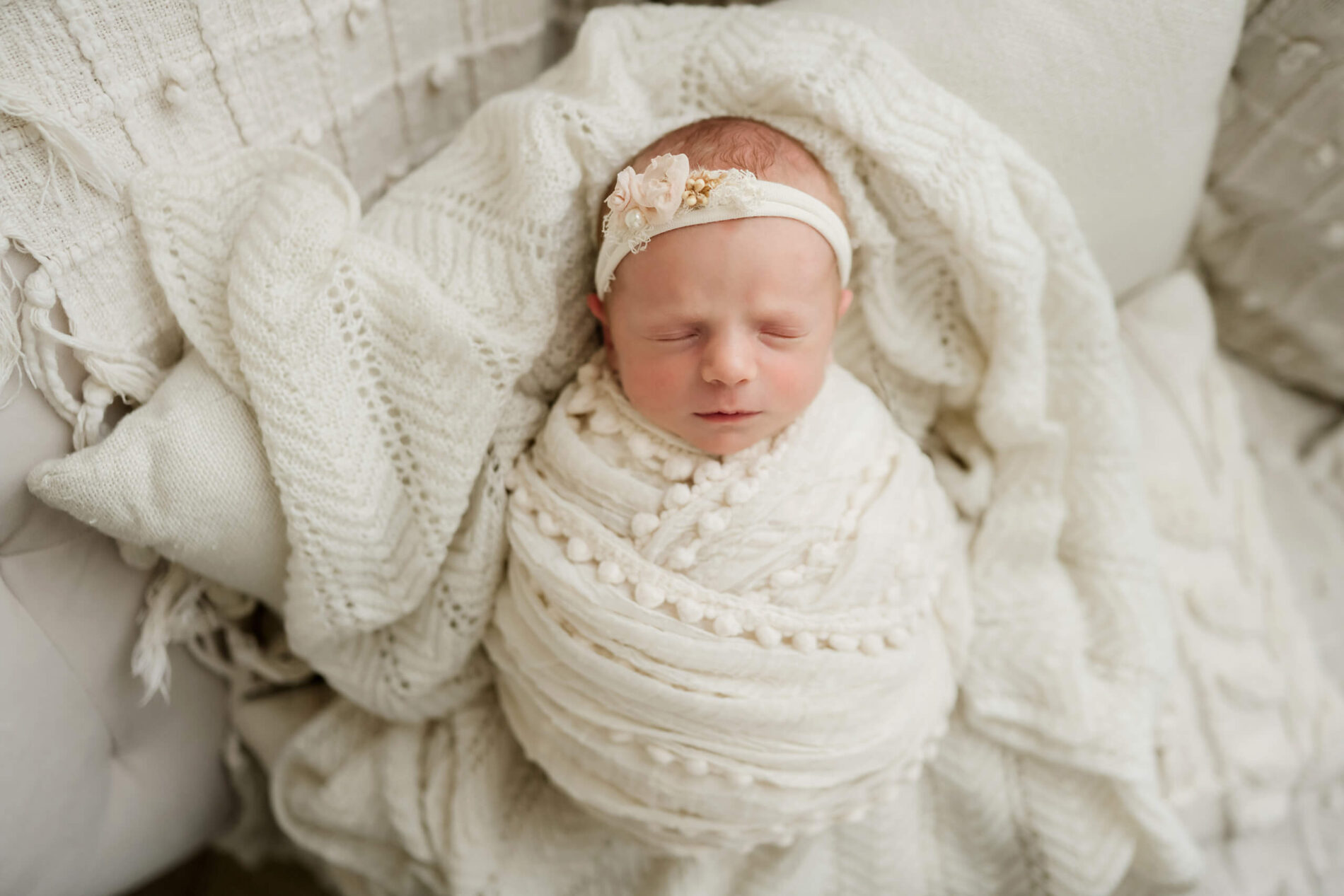 Natural newborn photography, sleeping girl swaddled in white blankets, lying on white blankets