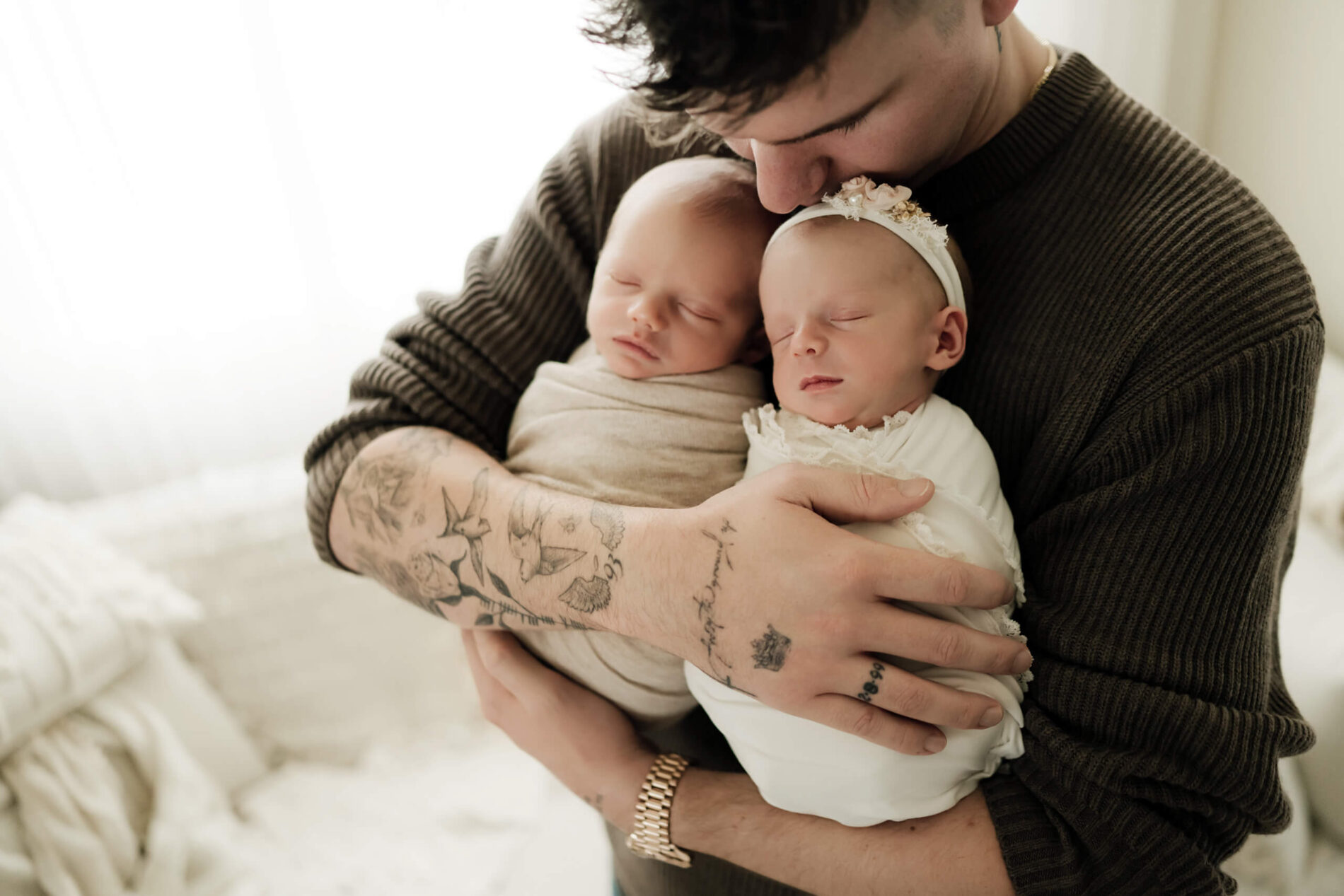 Twins newborn photography, dad lovingly holding his sleeping son and daughter