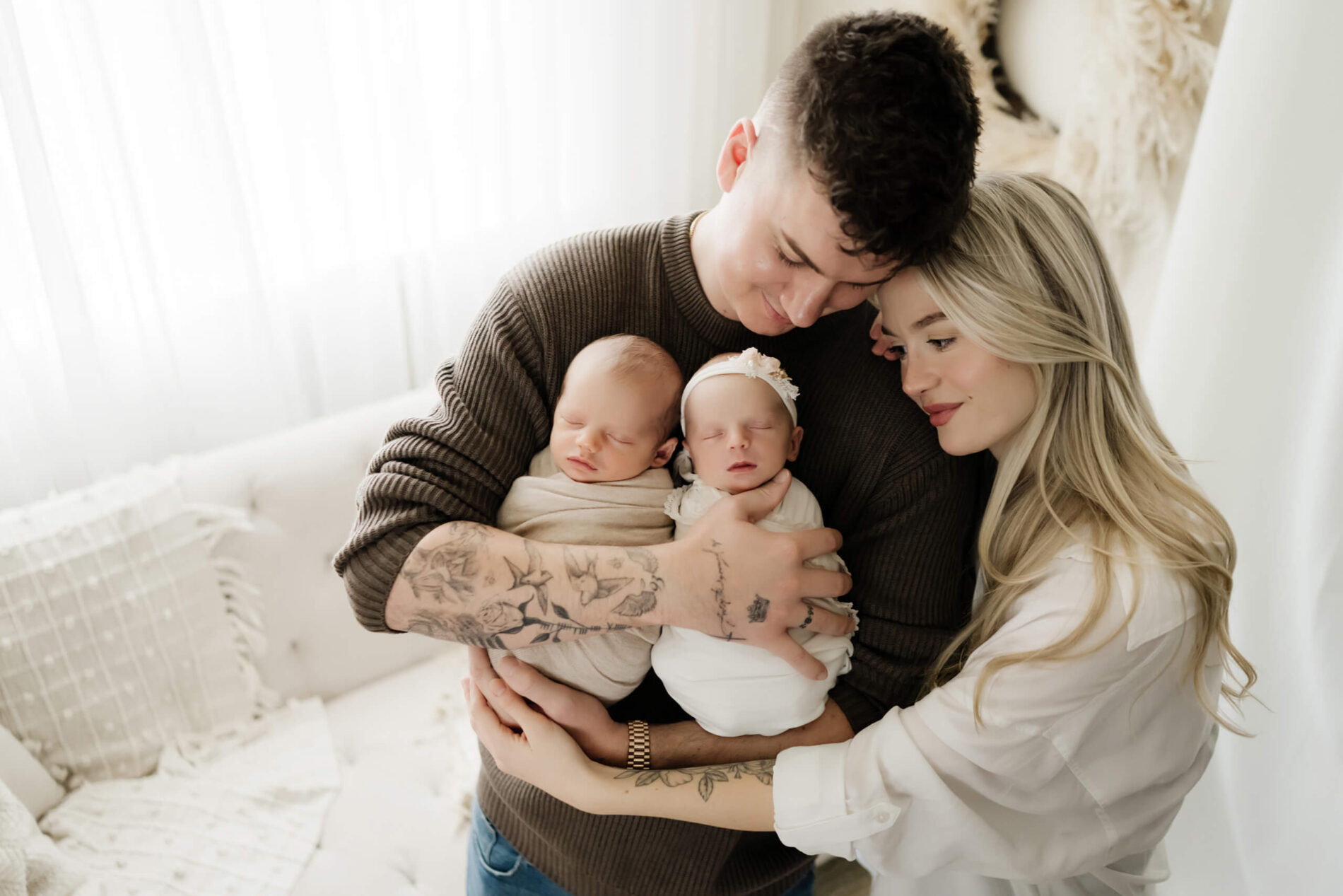 Twin newborn photography, dad hugging his son and daughter, with mom hugging dad on the side and looking at her kids