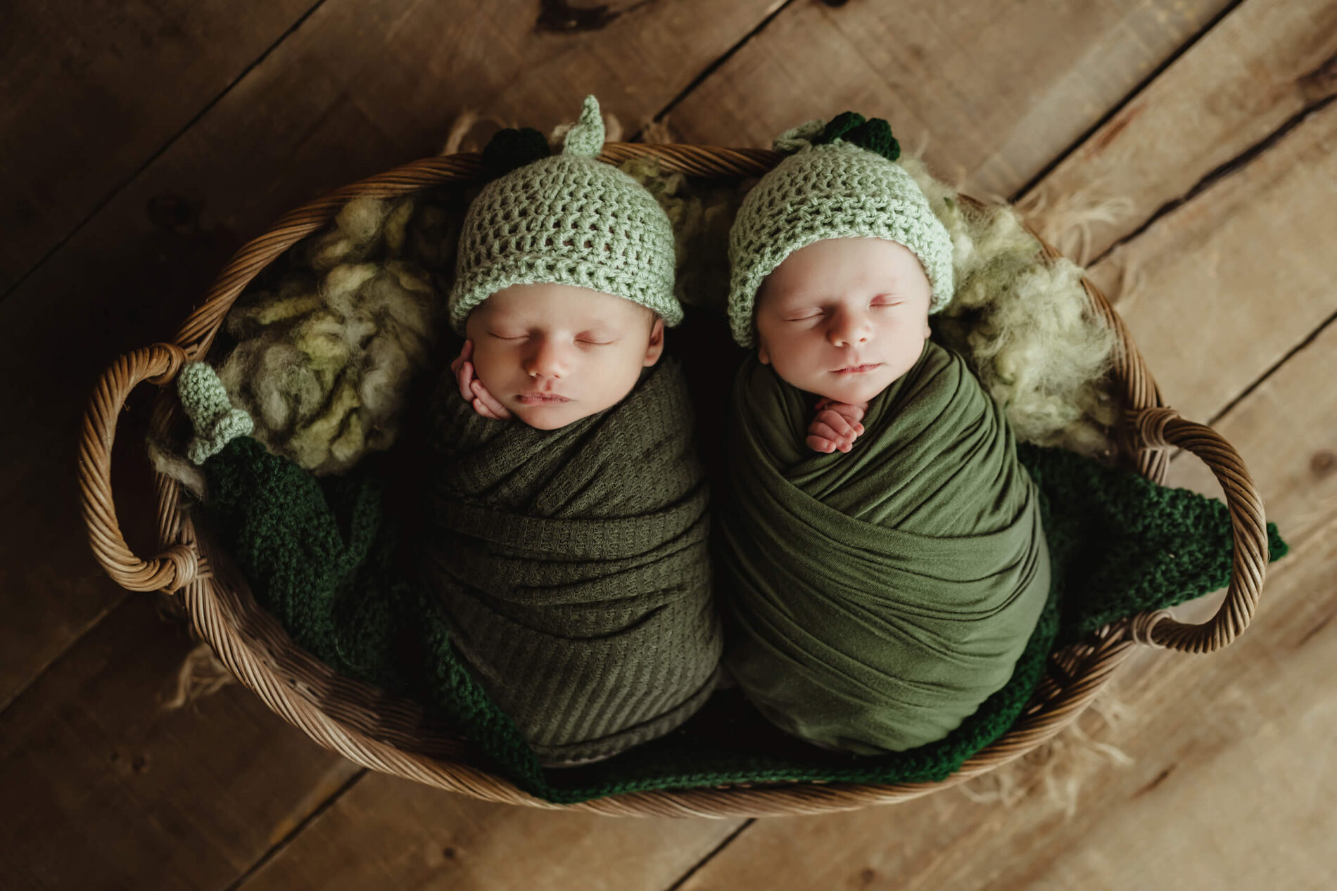 Twin newborn photography idea, boy and girl wrapped in green blankets, wearing green bonnets, posed in a basket