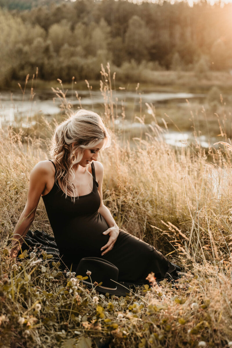 Pregnancy photo shoot in Bellevue, pregnant woman in a dress sitting in field with tall grass